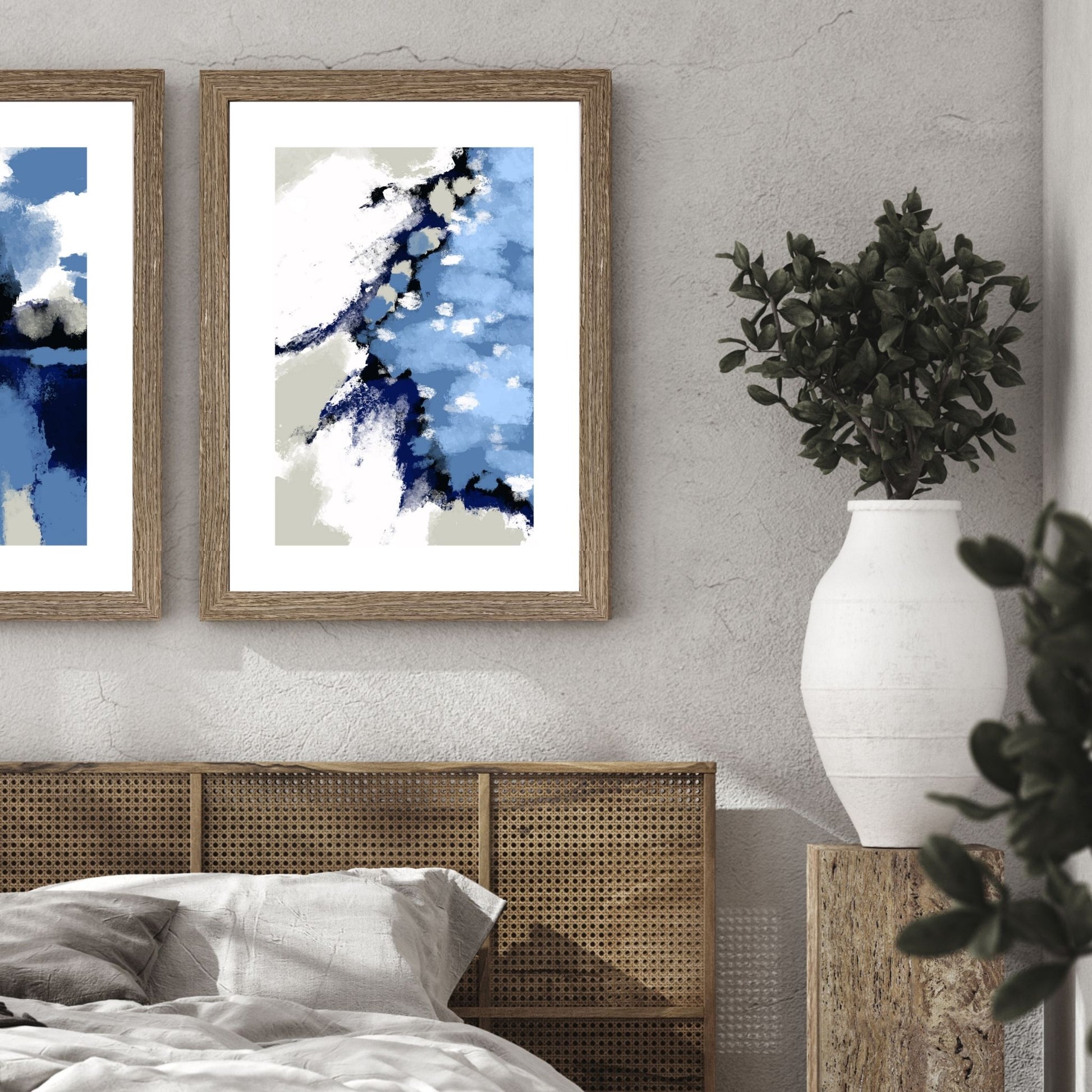 Blue Abstract No1 er en grafisk plakat med et motiv i blåfarger med innslag av hvit og beige. Plakaten har en bred hvit kant som gir bildet dybde og fremhever motivet. Illustrasjon viser plakaten i en ramme i eik på en vegg over en seng. 