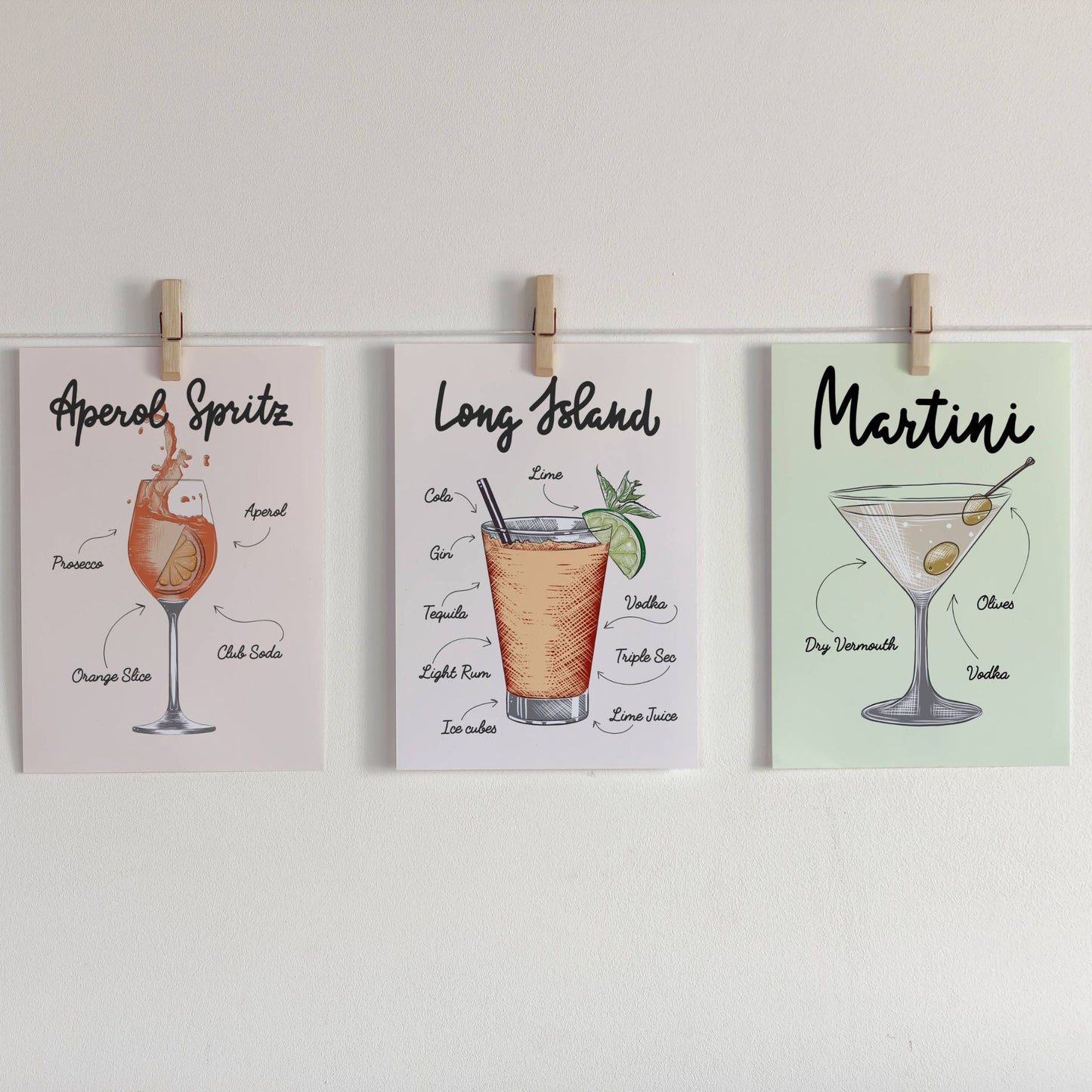 Illustrasjon som viser Lemonade, Bloody Mary og Aperol Spritz Cocktailplakater på lys bakgrunn som er festet med klyper på en snor.