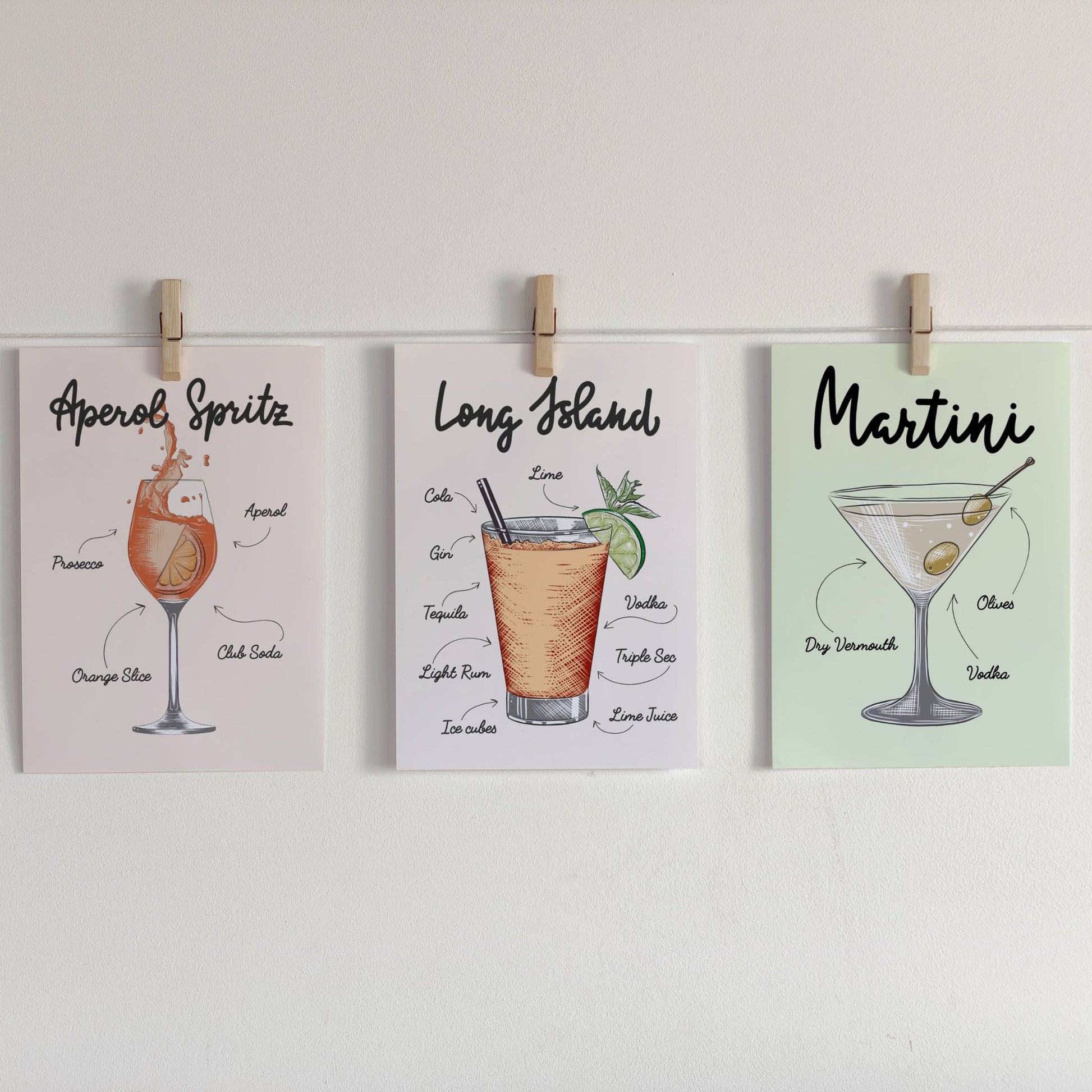 Illustrasjon som viser Lemonade, Bloody Mary og Aperol Spritz Cocktailplakater på lys bakgrunn som er festet med klyper på en snor.