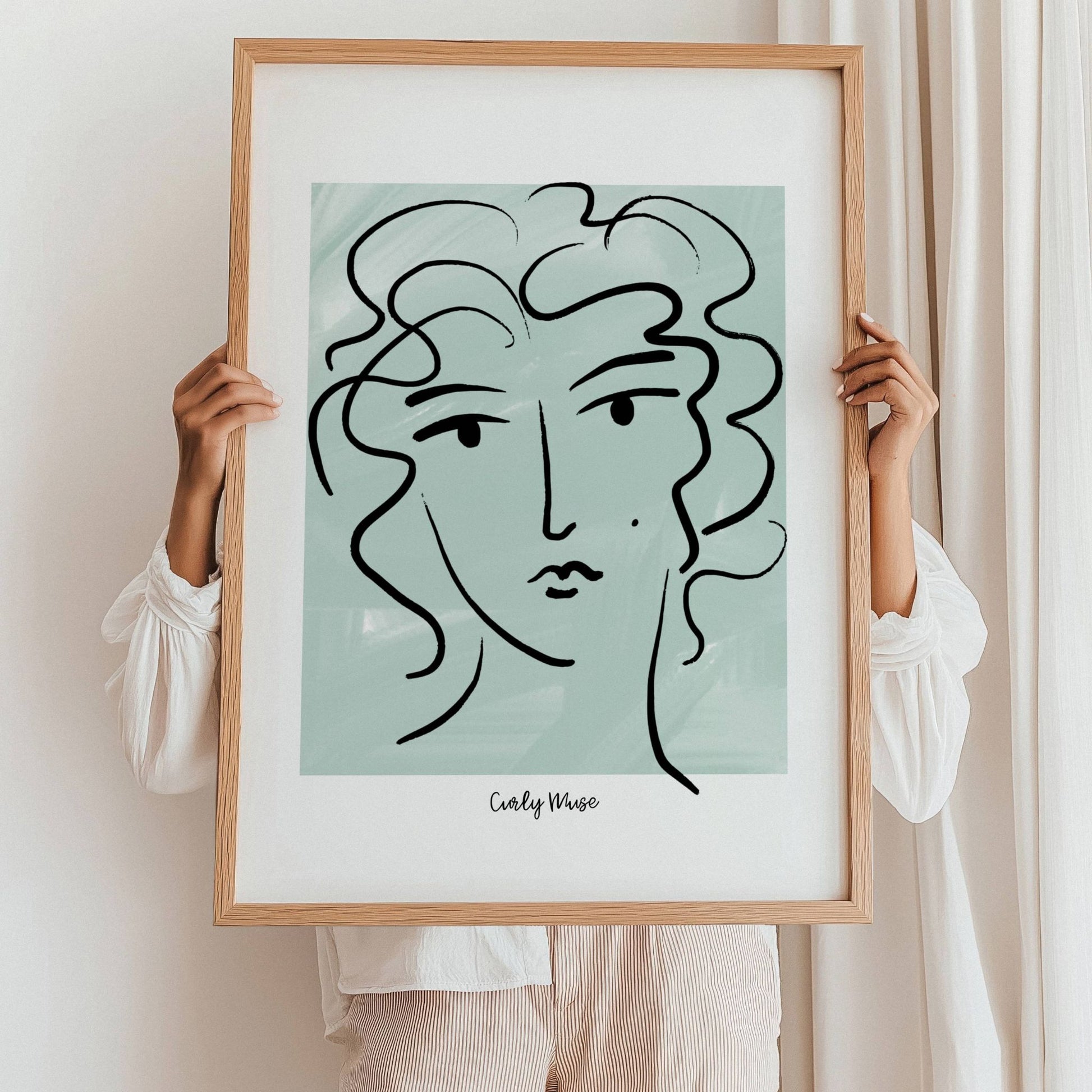 Løft rommet med en kunstnerisk vri med Curly Muse – Moderne Portrettplakat. Illustrasjon viser plakat i eik ramme.