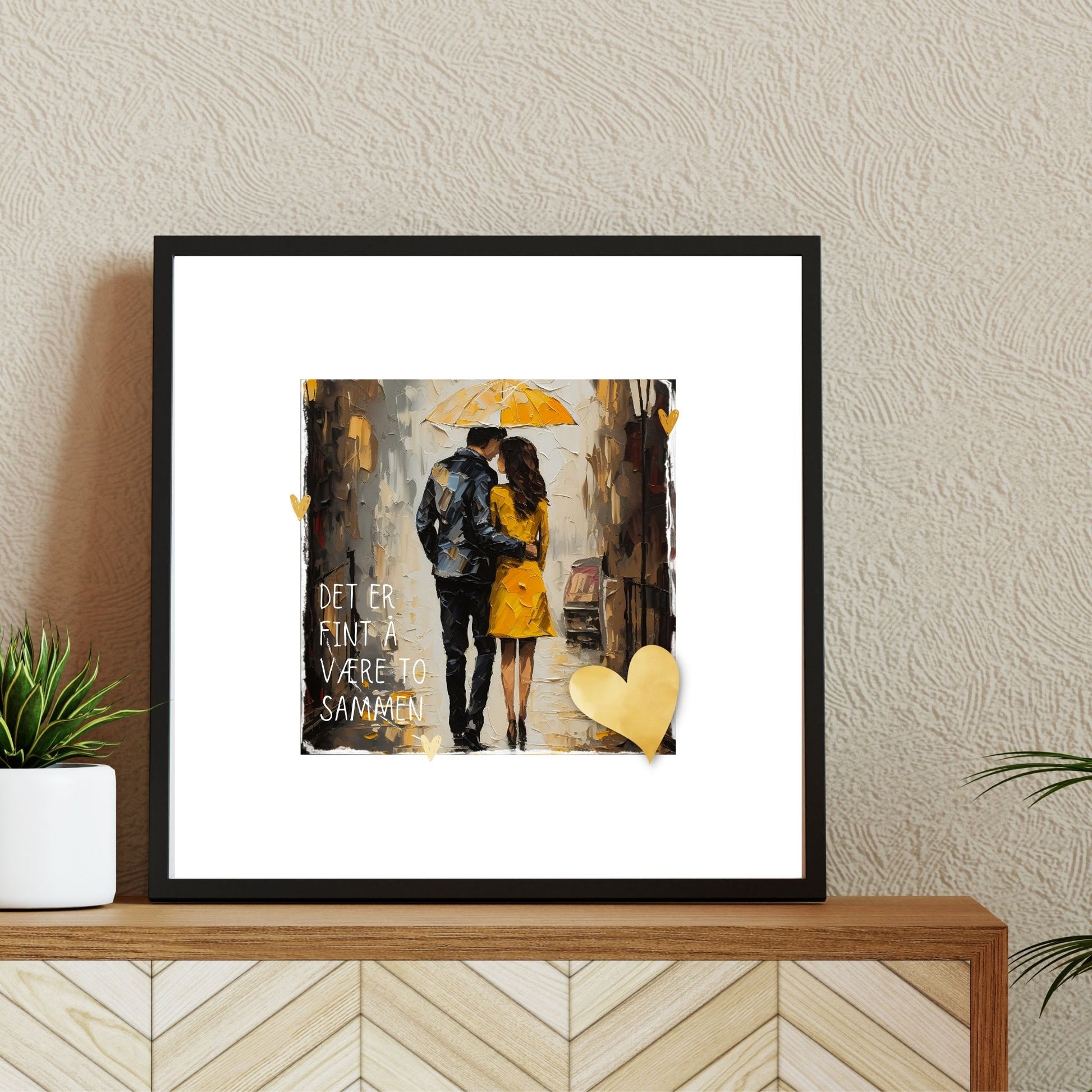 Plakat med lysegult hjerte og tekst "Det er fint å være to sammen" - og et motiv med et kjærestepar som går under en gul paraply. Bildet har en hvit kant på 4 cm. Illustrasjon viser plakat i ramme.