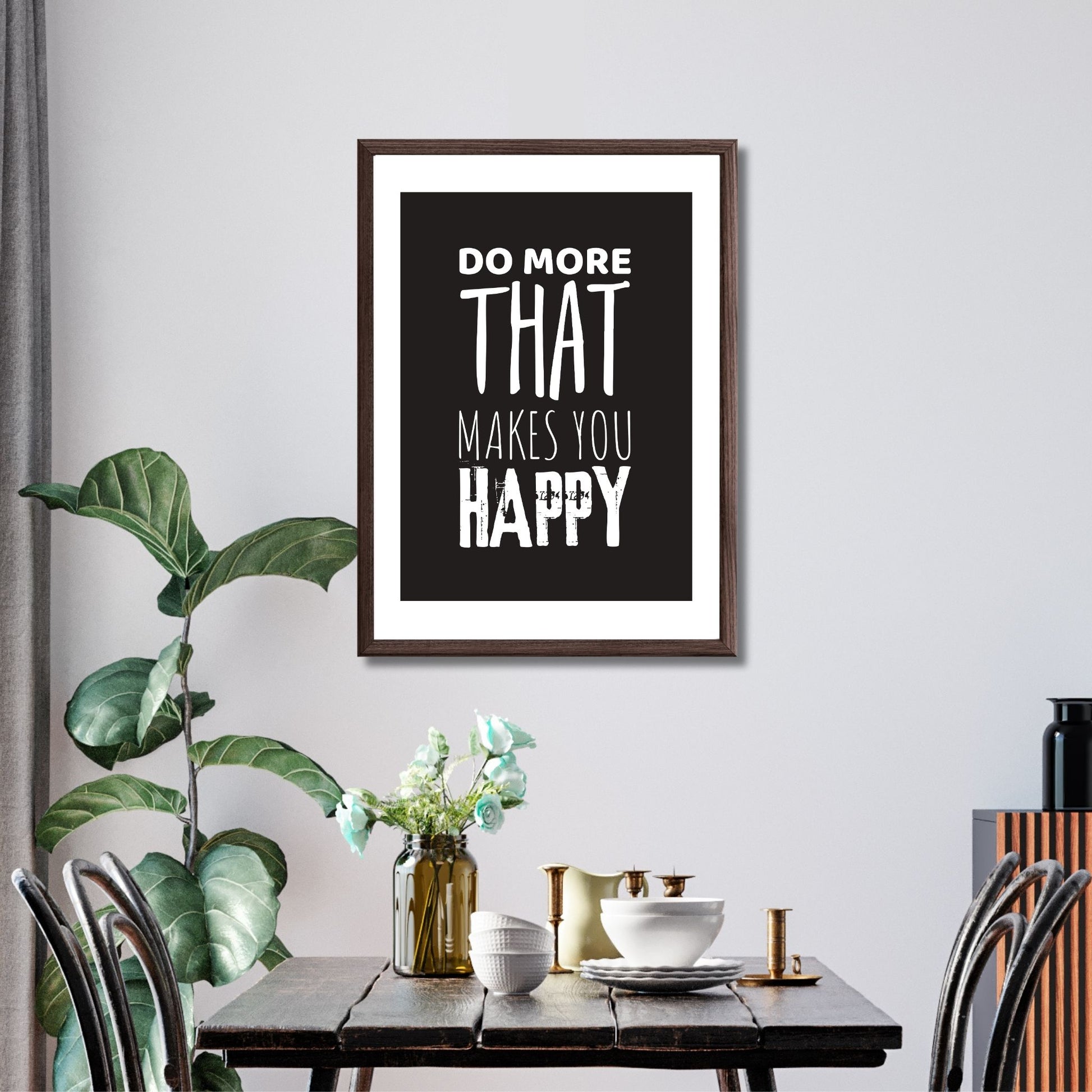 "Do more that makes you happy" tekstplakat. Hvit skrift på sort bakgrunn. Illustrasjon viser plakat i ramme med passepatout på en vegg i en spisestue.
