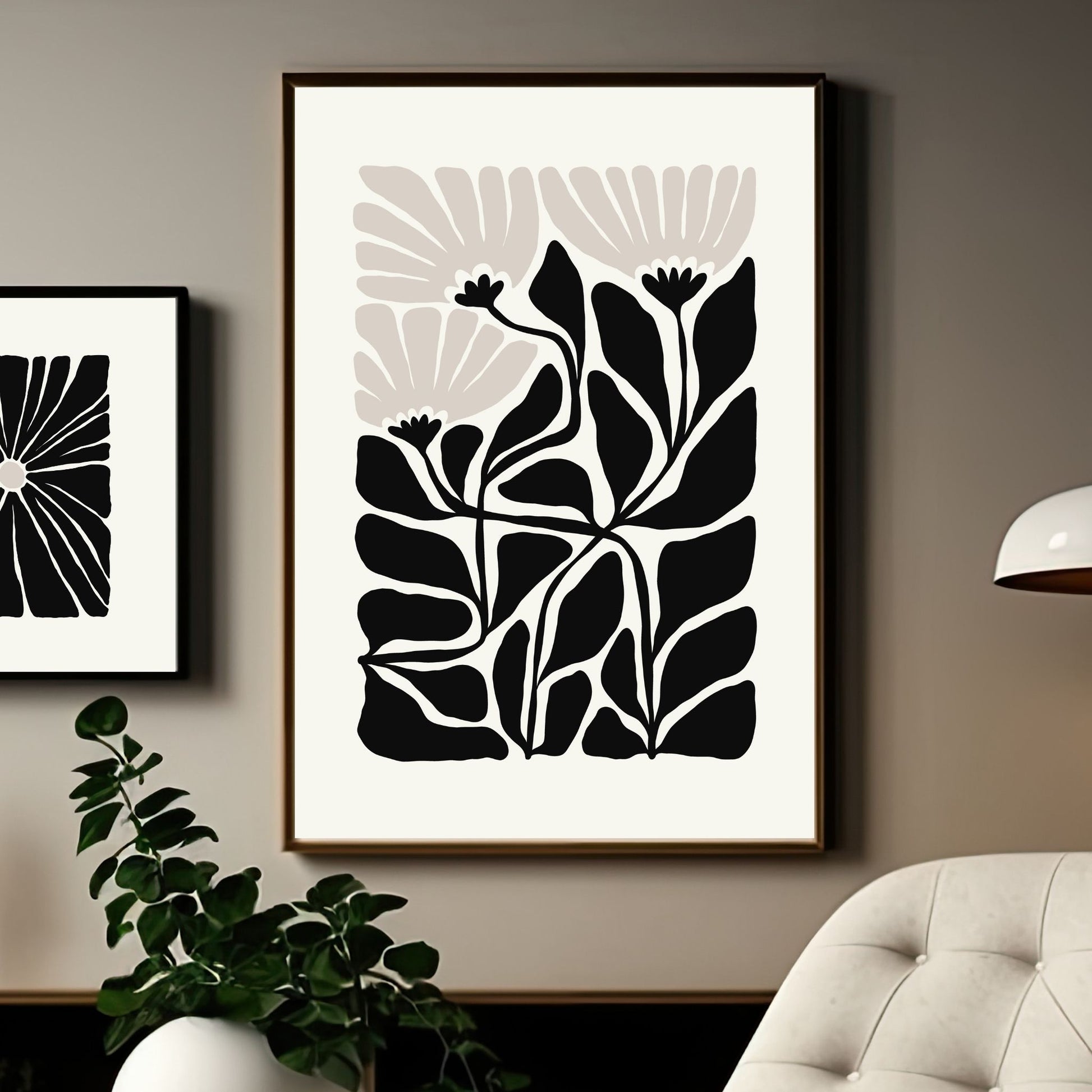 Bildet viser en grafisk plakat i abstrakt, floralt mønster i sort, beige og dempet hvit bakgrunn. Plakaten har en bredt kant i dempet hvit farge rundt og henger i sort ramme på en lys brun vegg.