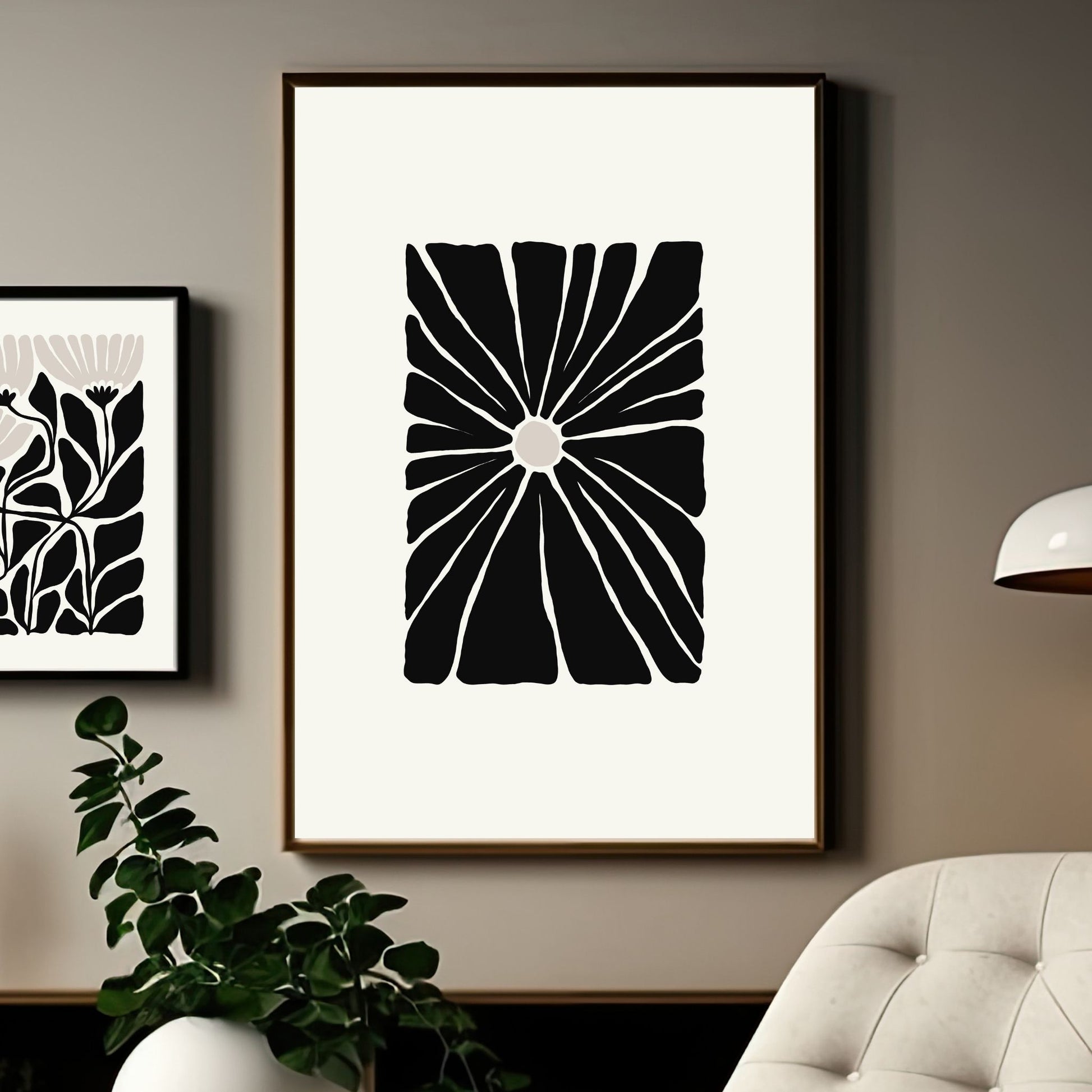 Miljøbilde som viser en grafisk plakat i abstrakt, floralt mønster i sort, beige og dempet hvit bakgrunn. Plakaten har et bredt felt rundt i bakgrunnsfarge, og henger i sort ramme på en lys brun vegg 