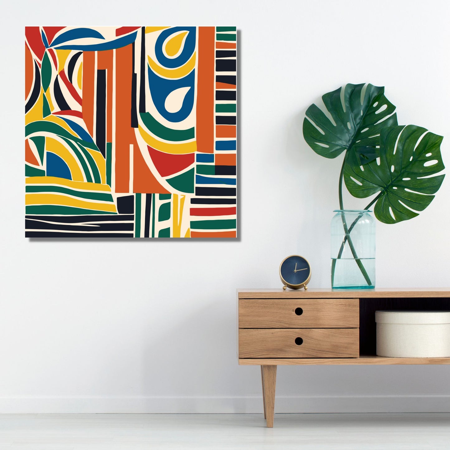 Kvadratisk plakat med abstrakt mønster i fargene rød, gul, blå, grønn, sort, oransje og lys beige bunnfarge. På bildet er den på lerret og henger på en lys vegg. Den henger ved siden av en komode i eik. På komoden står det en vase med to grønne blader, og en vekkeklokke med blå urskive.