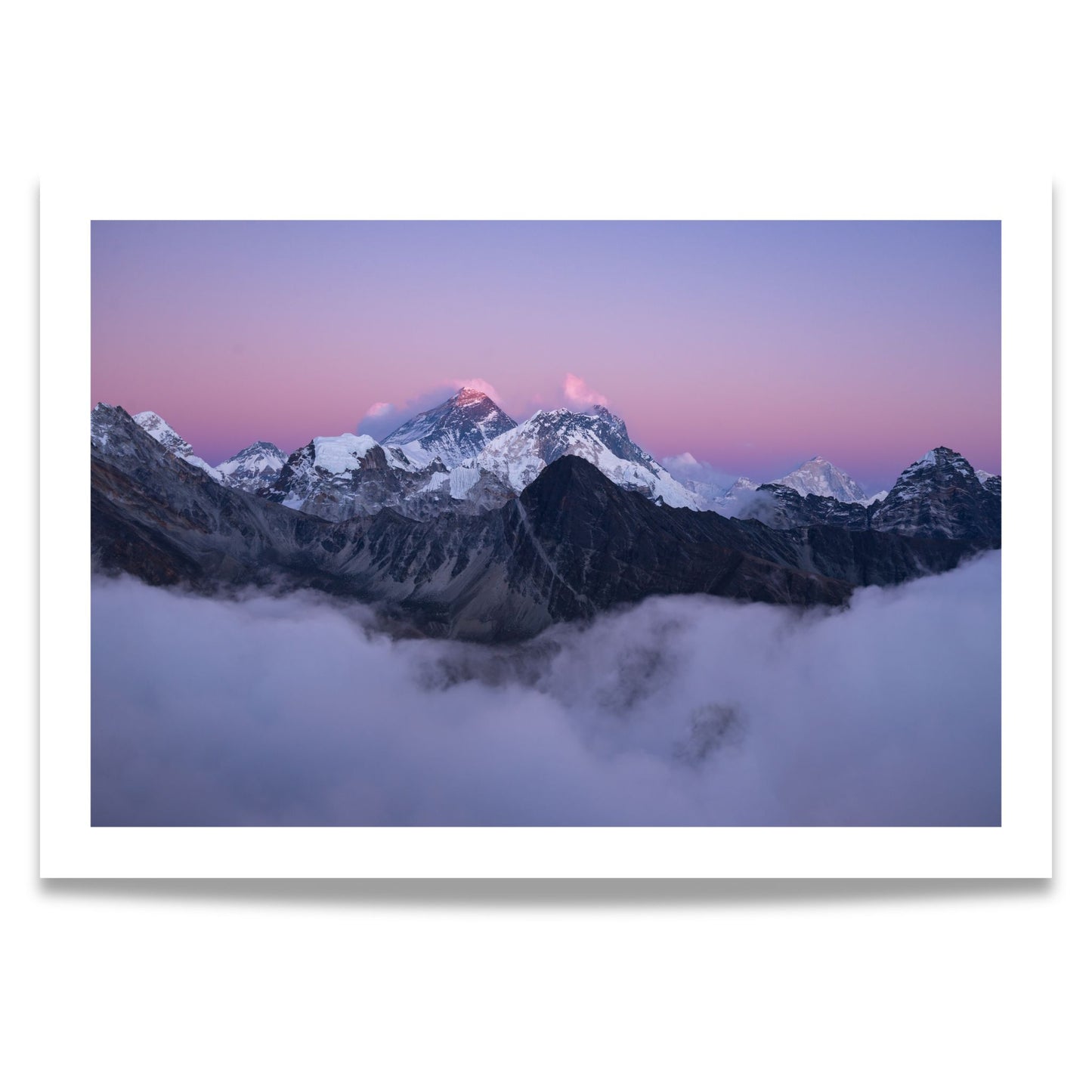 Dette fantastiske bildet viser Mount Everest, dekket av snø og innhyllet i tåkedekte skyer under en vakker, rosa-lilla skumringshimmel. 