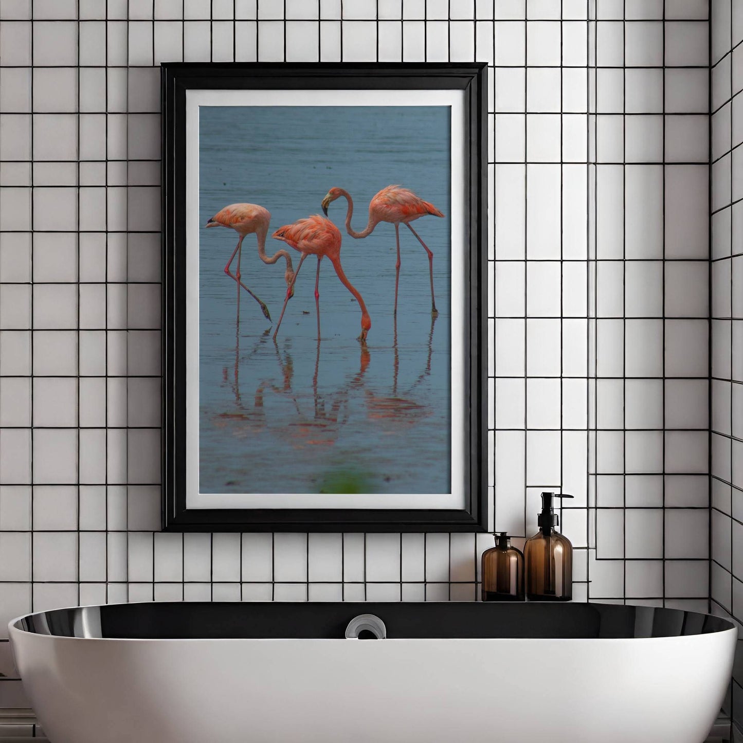 Dette fargerike naturmotivet fanger en gruppe flamingoer i stille vann, med vakre refleksjoner og rolige omgivelser. Illustrasjon viser motivet som plakat med passepartout i sort ramme.