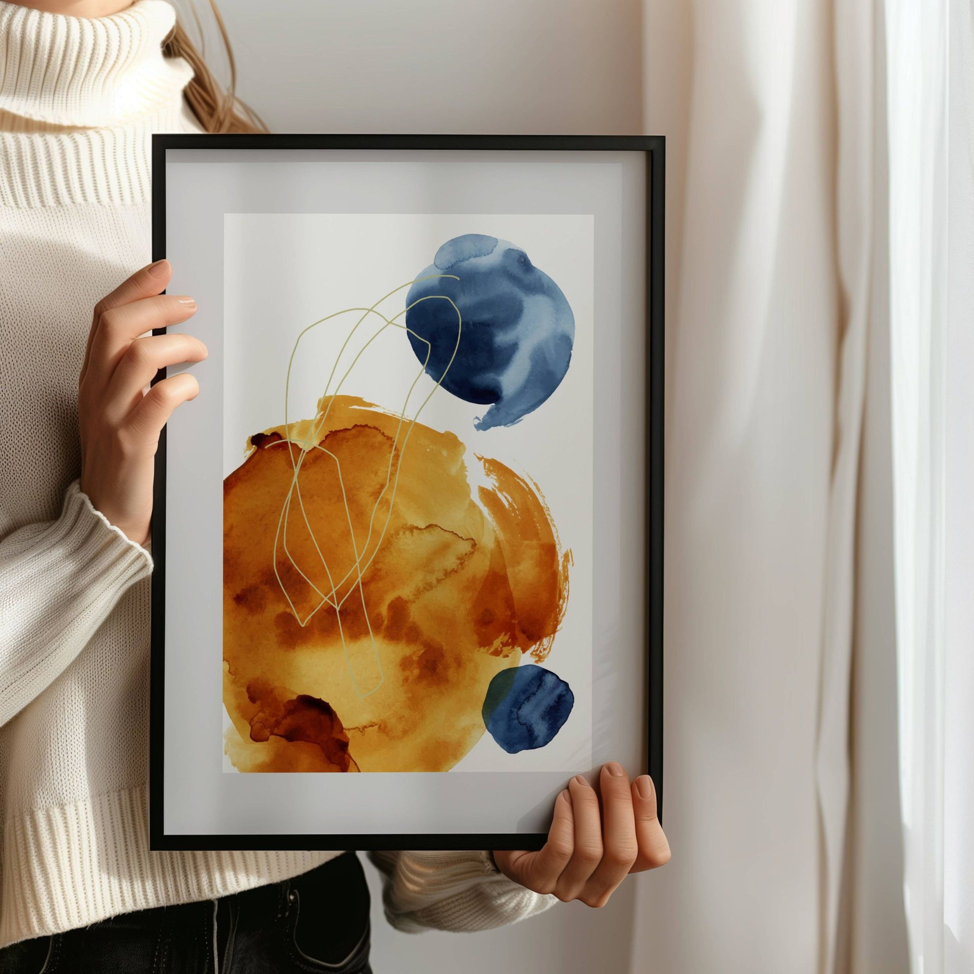 Golden Flow – abstrakt akvarellplakat er en moderne kunstplakat som kombinerer varme okertoner med dype blå kontraster. Illustrasjon viser plakat i sort ramme.