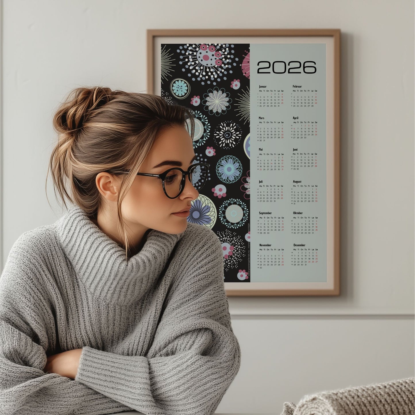 Grafisk kalender 2026 med pastellfargede abstrakte sirkler og mønstre på sort bakgrunn, med tydelig kalender og norske helligdager. Illustrasjon viser kalender i eik ramme.