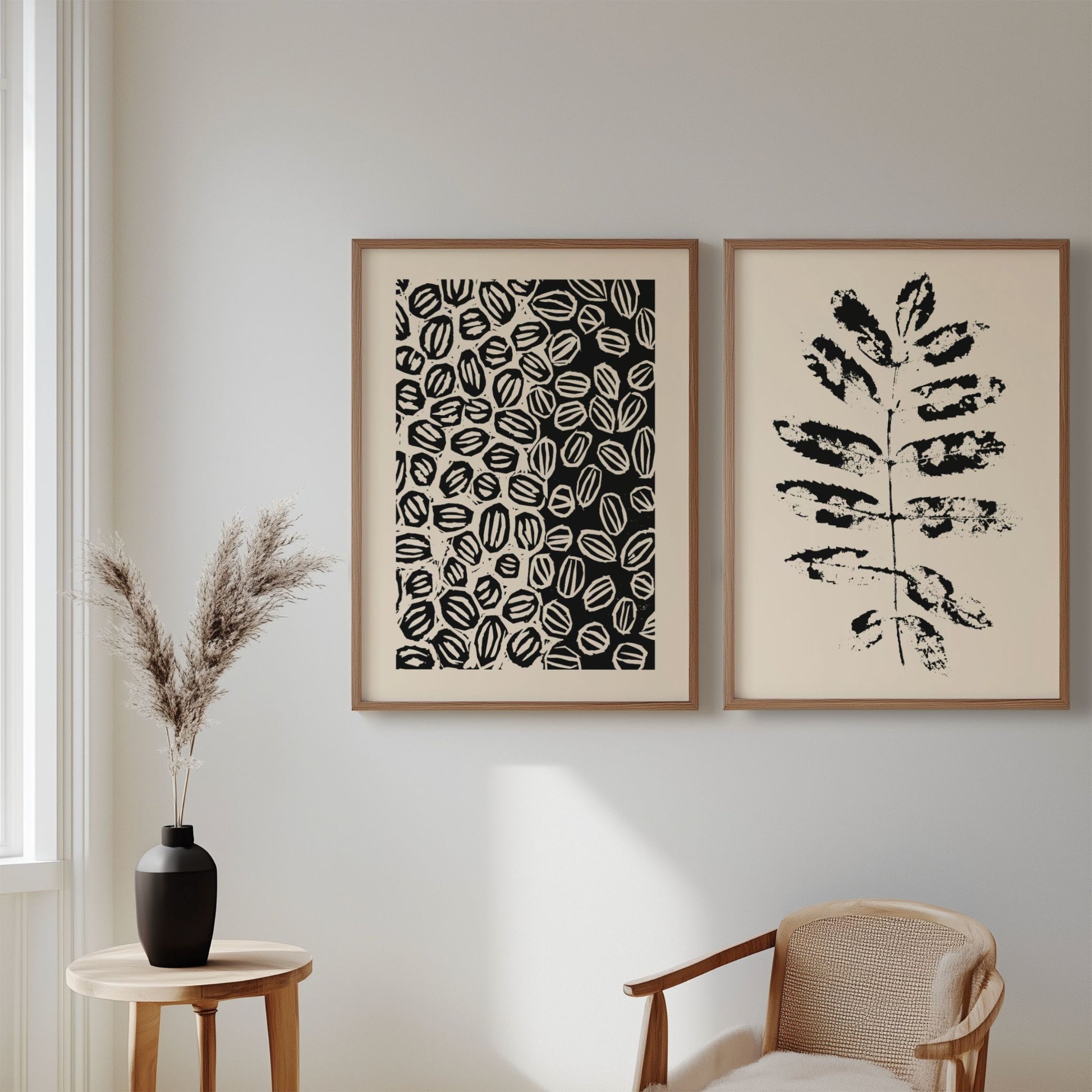 Illustrasjon viser plakatene Grafisk og Abstrakt Mønster Plakat og Minimalistisk Botanisk Plakat – Abstrakt Svart Bladdesign som henger i eikerammer på en stuevegg.