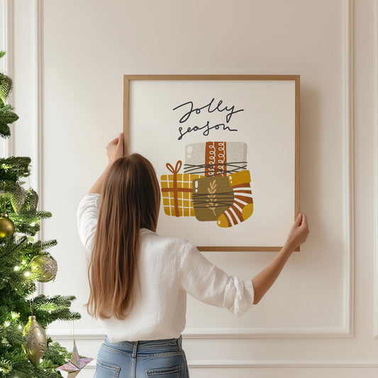 Et herlig motiv med teksten Jolly Season og en samling gaver pakket inn i varme jordfarger. Illustrasjon viser plakat i eik ramme.