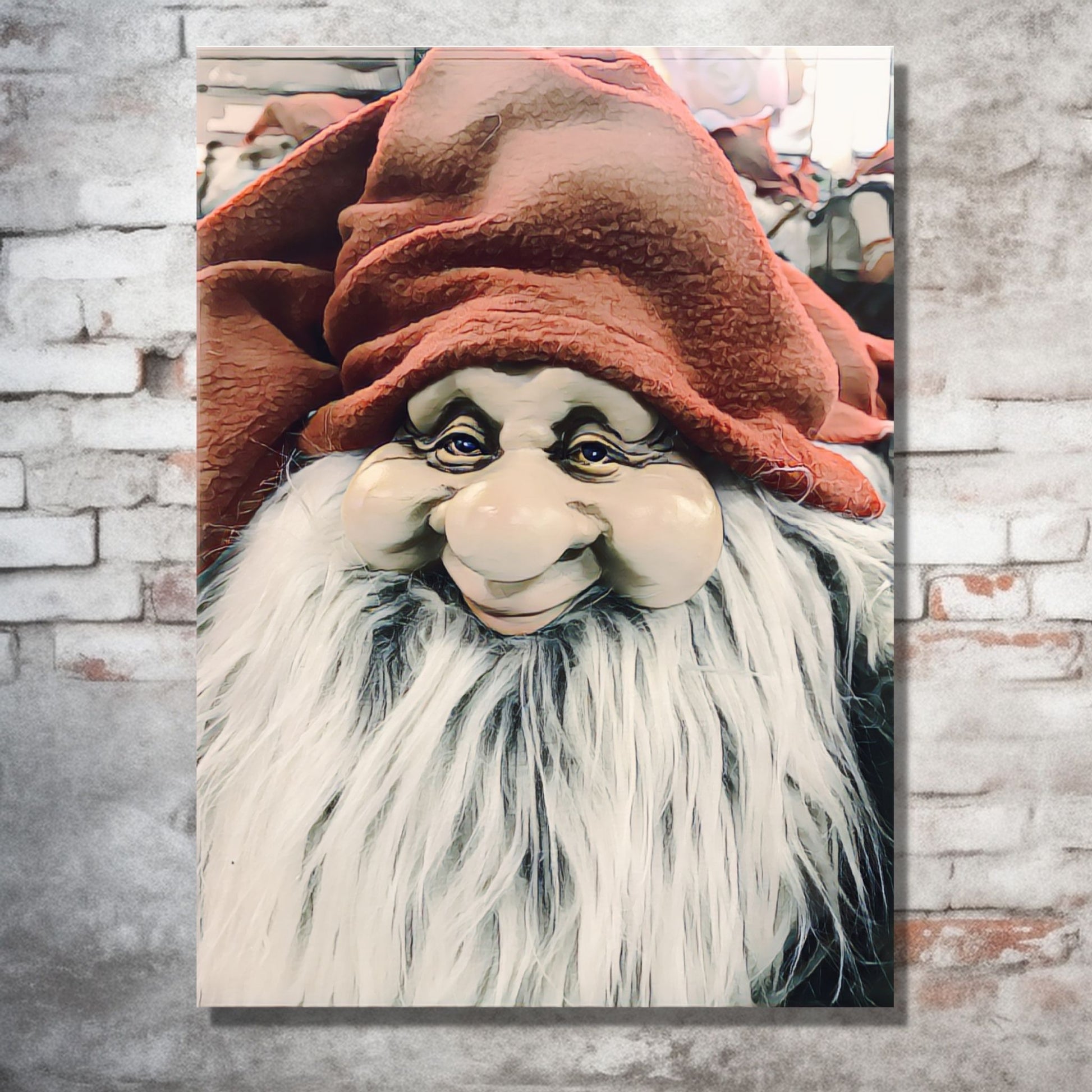 Grafisk motiv av ansiktet til en julenisse med stort, hvitt skjegg og rød nisselue. På bildet henger nissemotivet som lerretsbilde på en murvegg. Under bildet står det en grønn kommode, og ved siden av et juletre og julepakker.