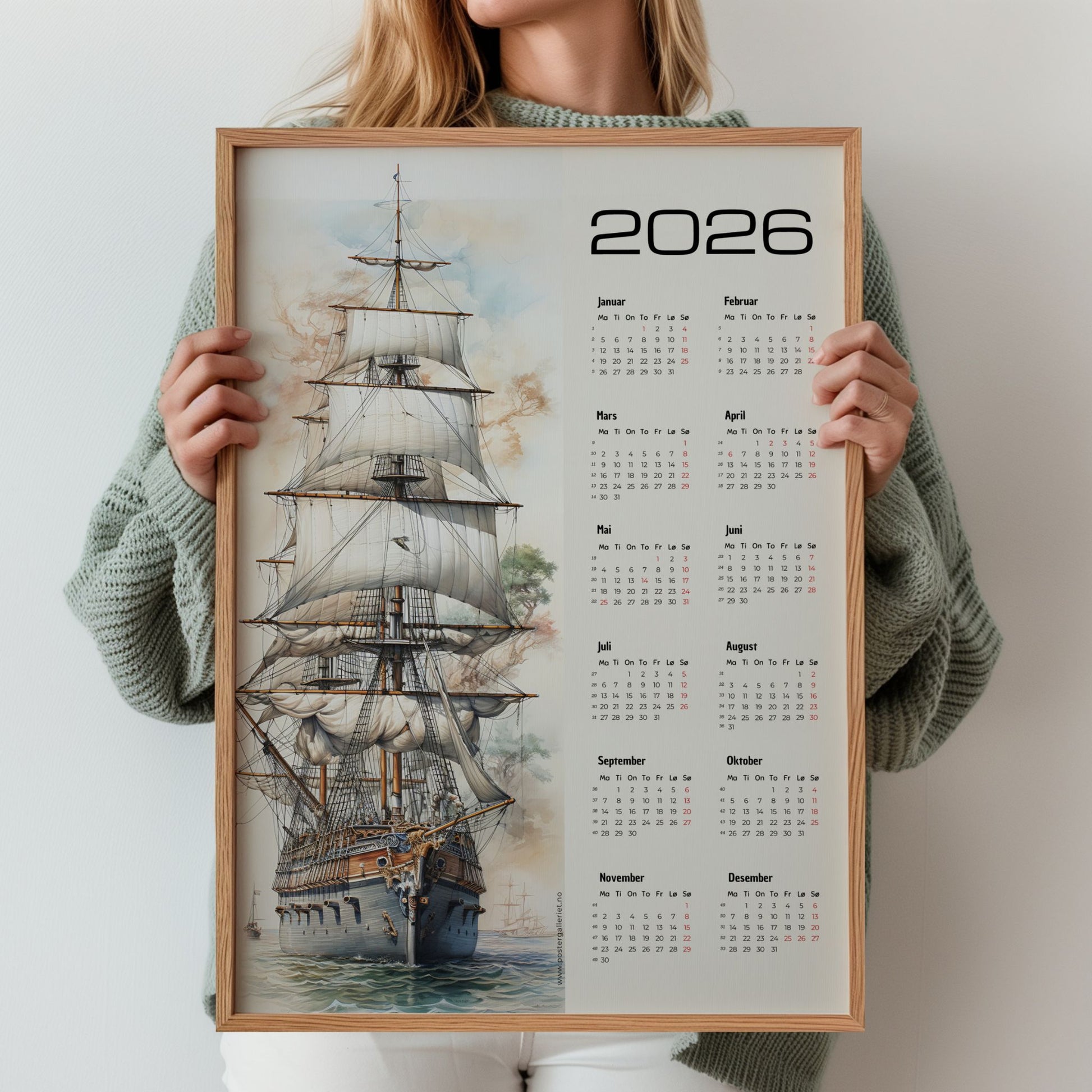 Kalender for 2026 med kunstmotiv av et stort seilskip i sollys, med alle årets måneder plassert i en tydelig kalenderkolonne til høyre. Illustrasjon viser kalender i eik ramme.