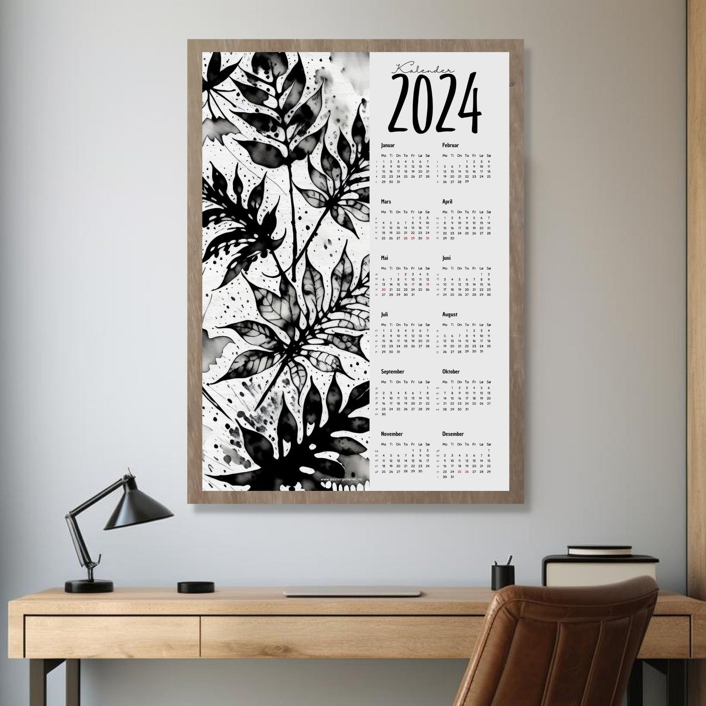 Kalender 2024 i grafisk print. Halve vertikale side har et grafisk floralt motiv i sort og hvitt. Den andre halvdelen er påført 12 måneder med ukenummer og anmerket høytidsdager. Miljøbilde av kalender i eikeramme som henger på en vegg.