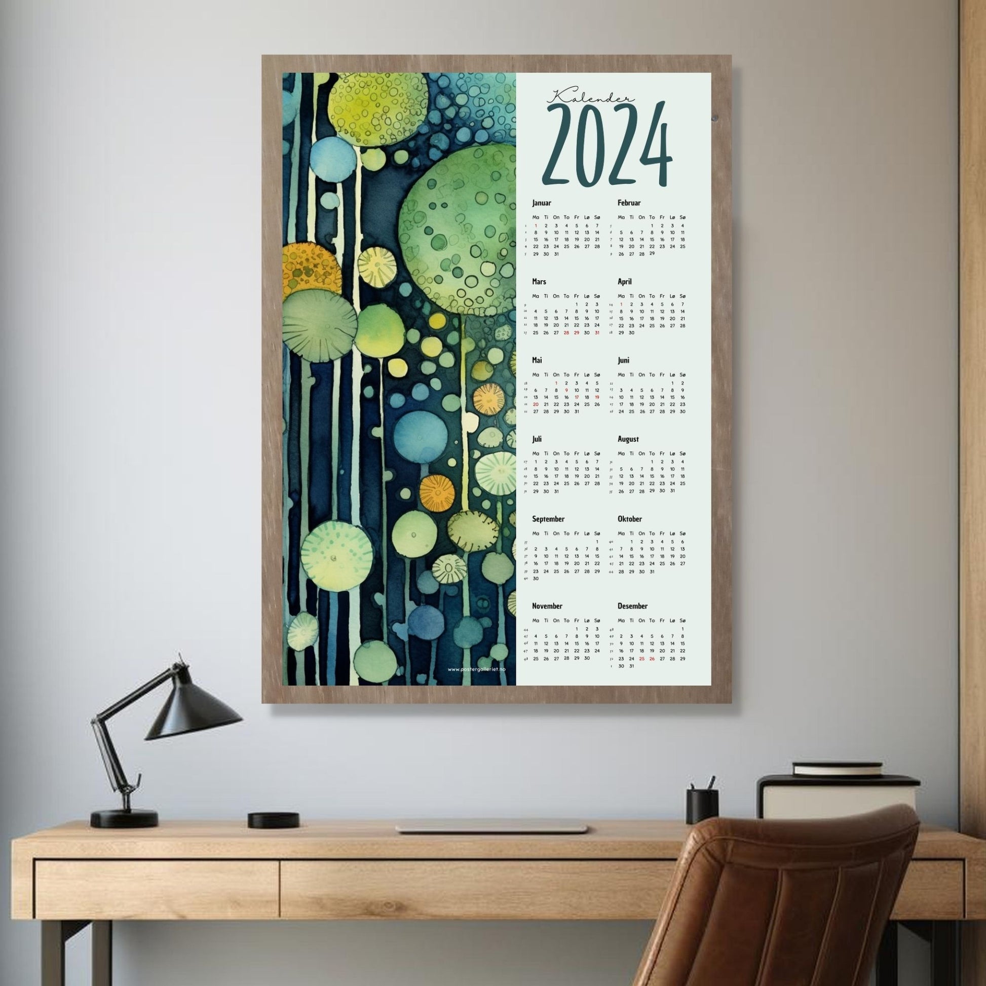 Kalender 2024 i grafisk print. Halve vertikale side har et grafisk motiv i grønne og blå fargenyanser. Den andre halvdelen er påført 12 måneder med ukenummer og anmerket høytidsdager. Miljøbilde av kalender i eikeramme som henger på en vegg.
