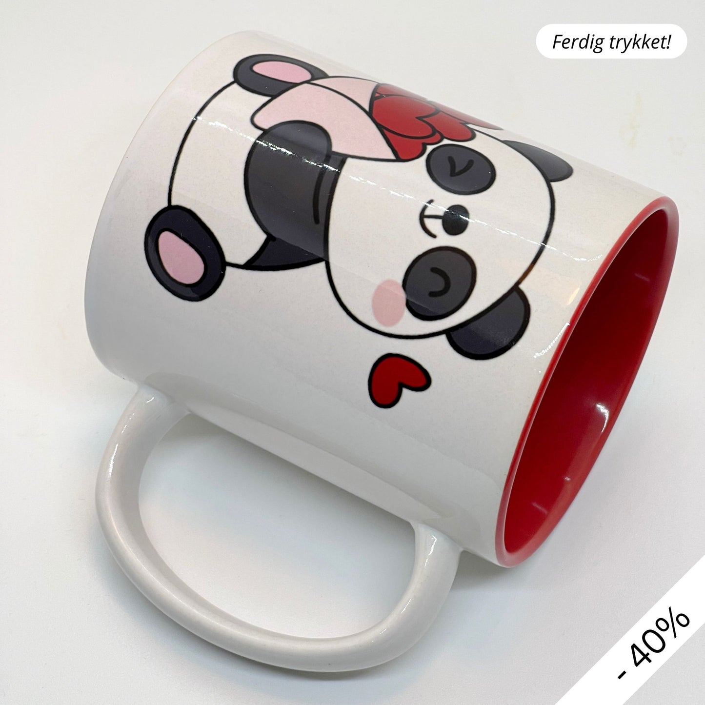 Krus i keramikk med en søt illustrasjon av en smilende panda som holder en bukett med røde hjerter, sammen med teksten "I LOVE YOU".  Innvendig farge på kruset er rødt.
