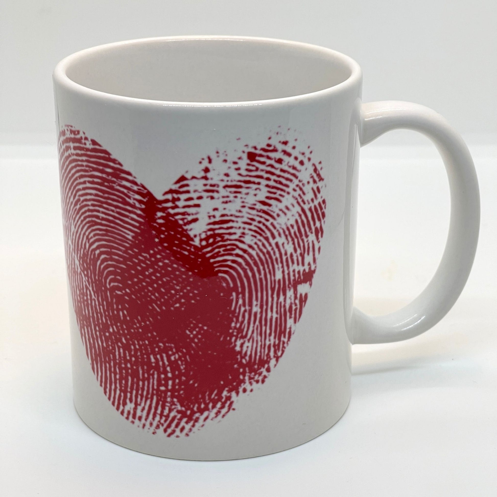 Krus i keramikk med teksten "YOU & ME" og en dristig typografi med et rødt fingeravtrykk-hjerte.