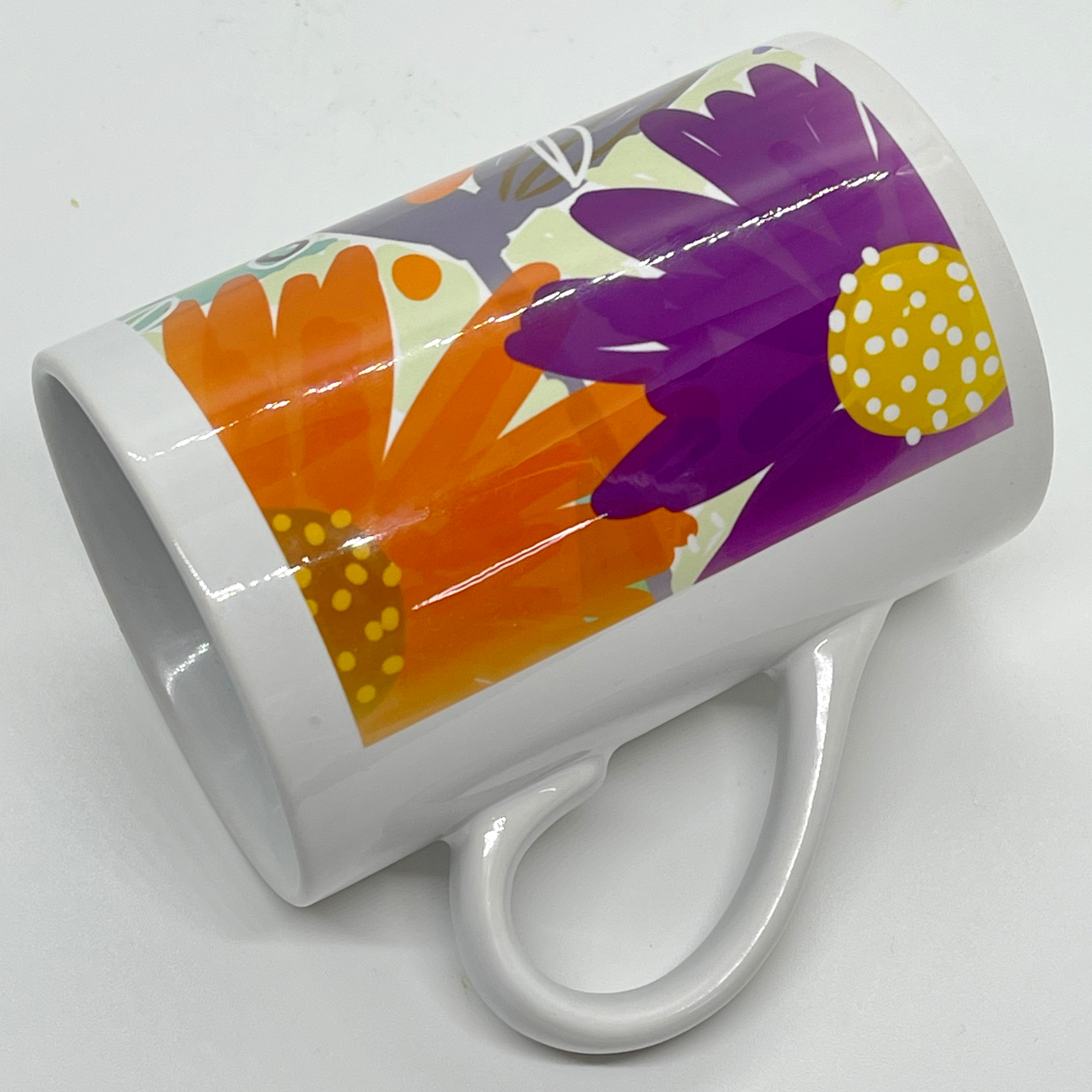 Hvitt krus i keramikk med håndtak. Kruset er påført et multifarget floralt trykk. Volum: 29 cl. Diameter: 7 cm. Høyde: 10,5 cm.