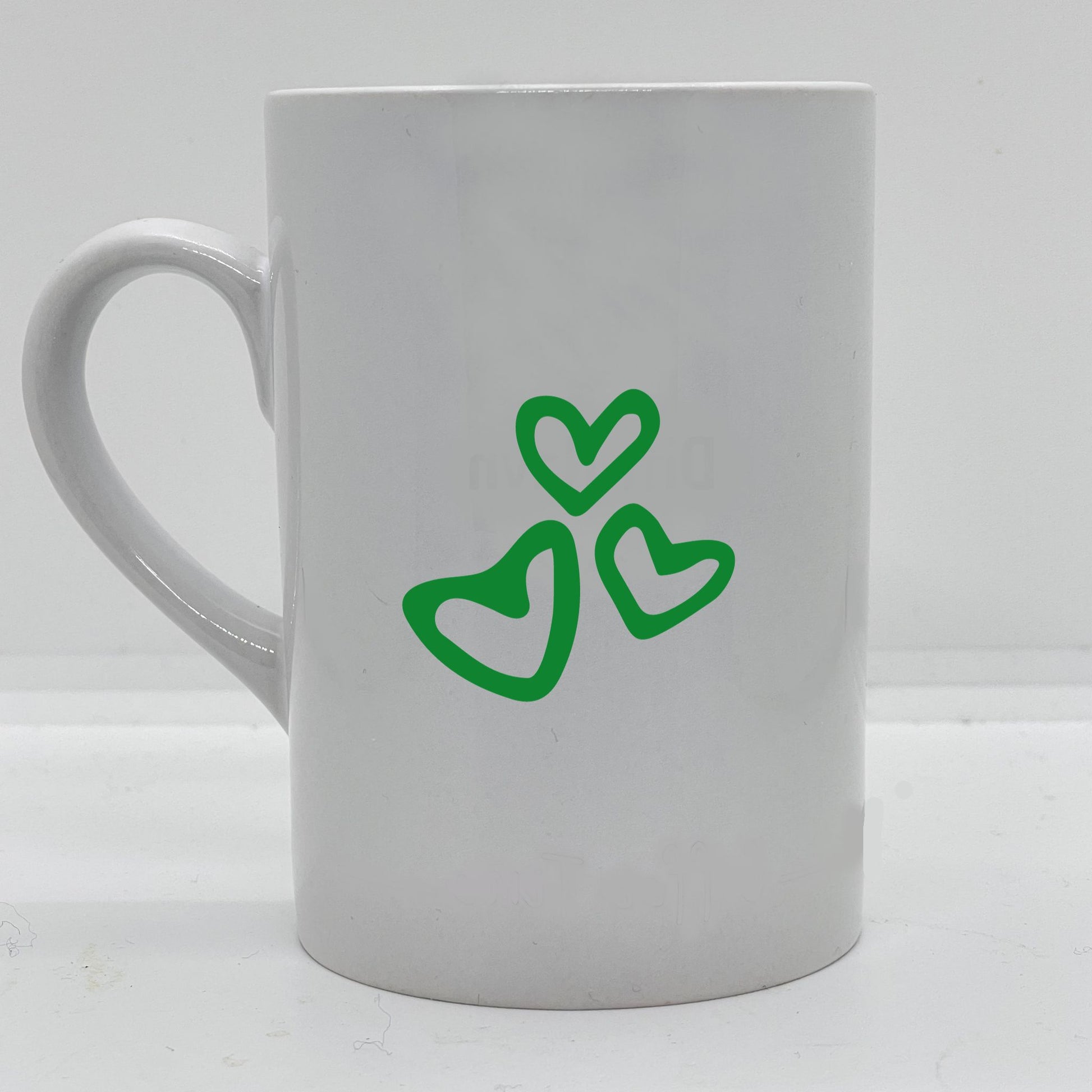 Krus i hvit keramikk med påskrift "Best son ever" på en side, og tre hjerter på motsatt side. Trykk i grønt og sort.
