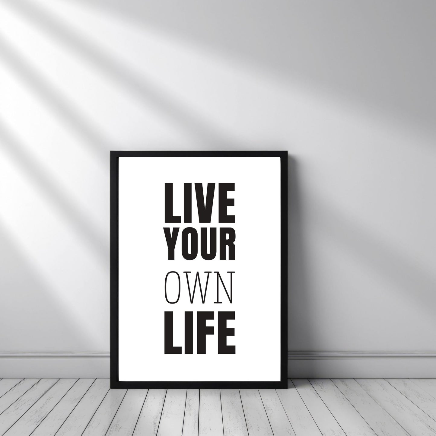 Grafisk plakat med sort skrift på hvit bakgrunn. Tekst på plakat "Live your own life" Illustrasjon viser plakat i sort ramme.
