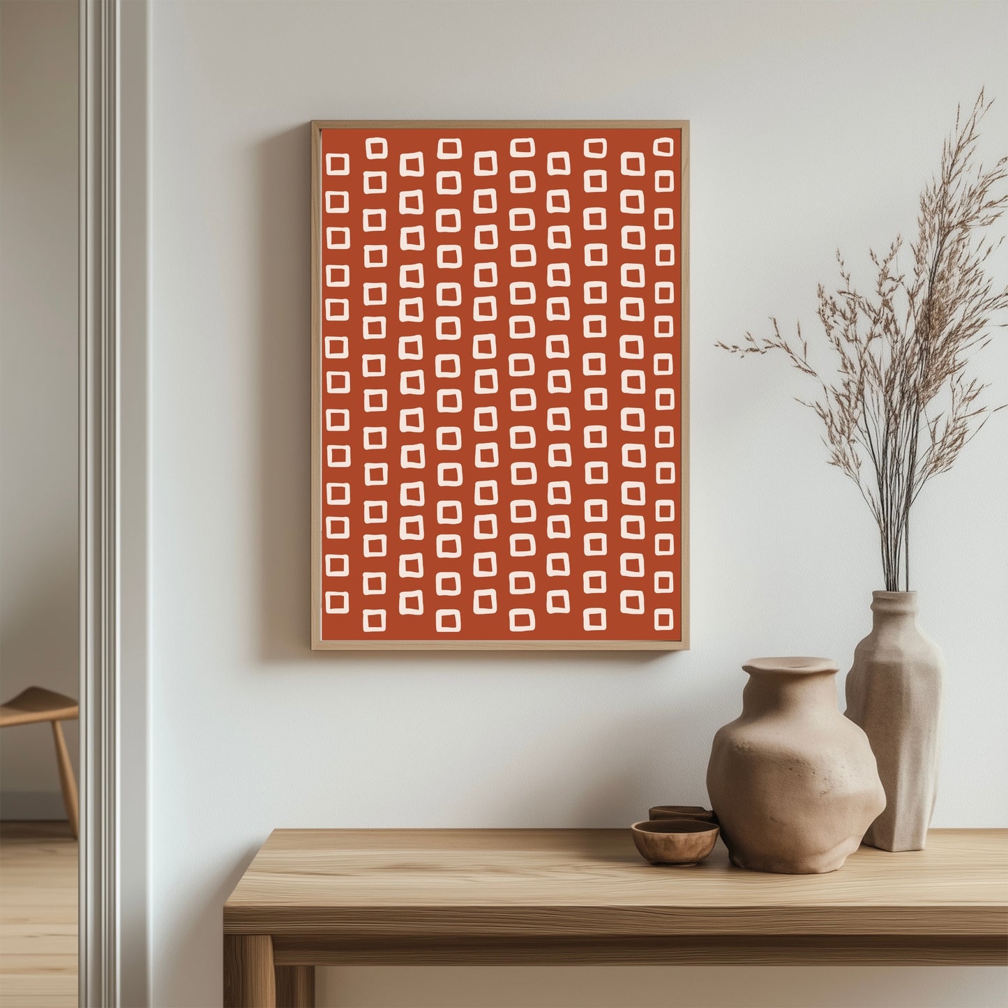 Dette unike designet kombinerer rustrøde toner med organiske, håndtegnede beige ruter som gir en leken og samtidig sofistikert estetikk. Illustrasjon viser plakat uten hvit kant i ramme av eik.