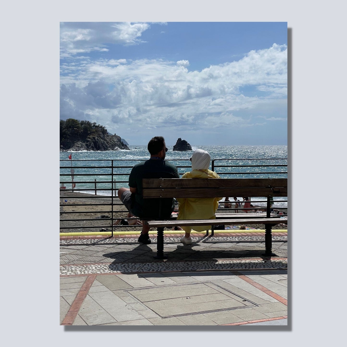 Motiv fra Montereosso al Mare, en av de fem byene i Cinque Terre ved Liguriakysten i Italia. Bildet viser blått middelhav og himmel som helt ned i vannet i horisonten. Her har et par funnet seg godt til rette på en av byens benker. Fri sikt utover Middelhavet så langt øyet ser. Til venstre på bildet går klipper ned i havet. Blå himmel er dekket med noen hvite skyer. Hav og himmel møtes ute i horisonten. Motivet på bildet er på lerret.