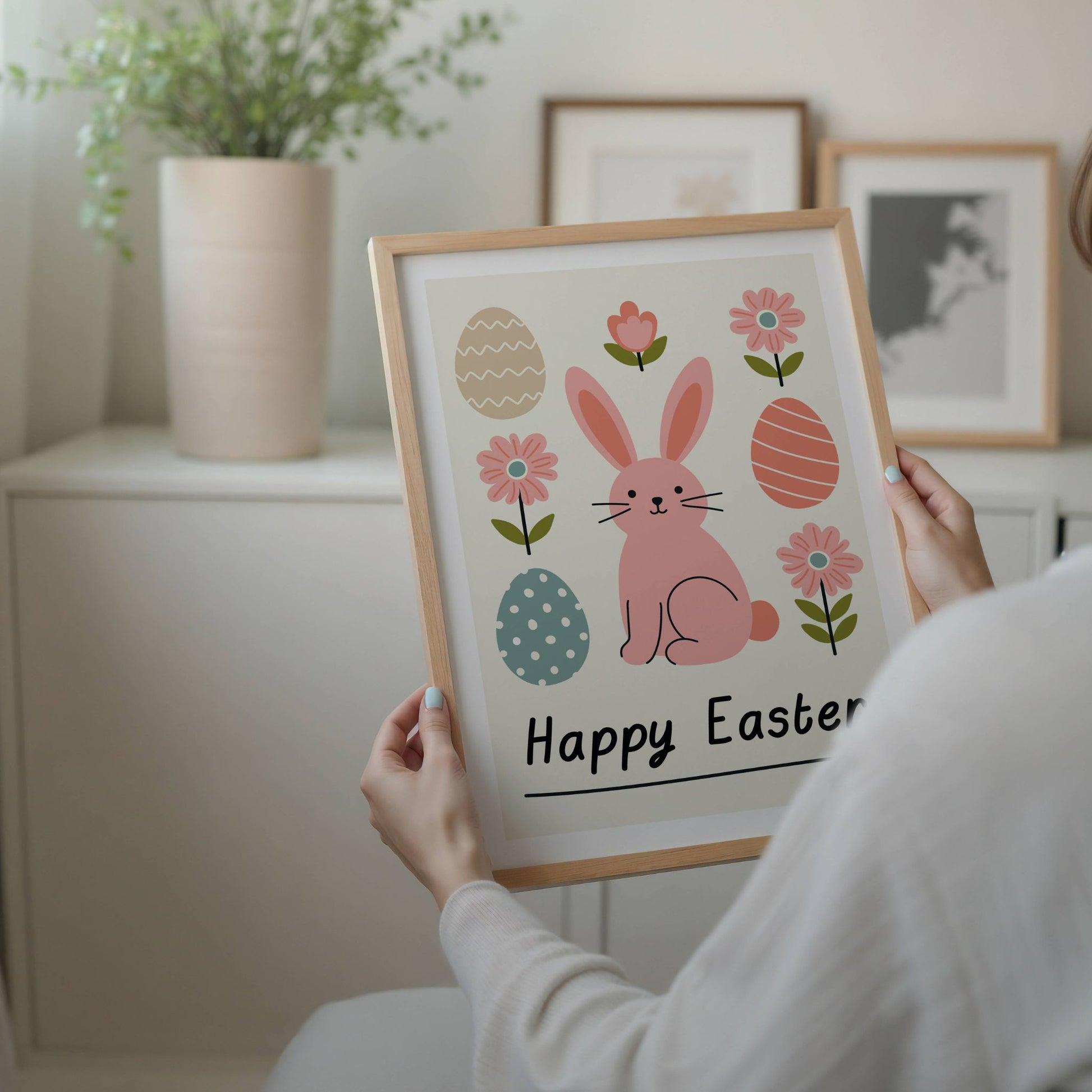 Denne vakre påskeplakaten har et minimalistisk og moderne design med en søt påskehare, påskeegg og blomster i myke pastellfarger. Illustrasjon viser plakat med hvit kant i eik ramme.