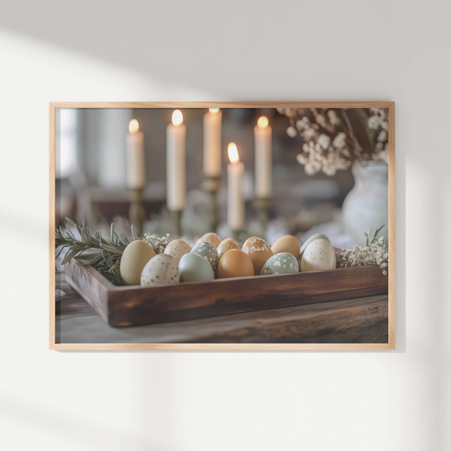 Med delikate pastellfargede egg i en rustikk trekasse, omgitt av grønne kvister og levende lys, formidler dette motivet en tidløs og elegant stemning. Illustrasjon viser motivet som plakat uten hvit kant i ramme.