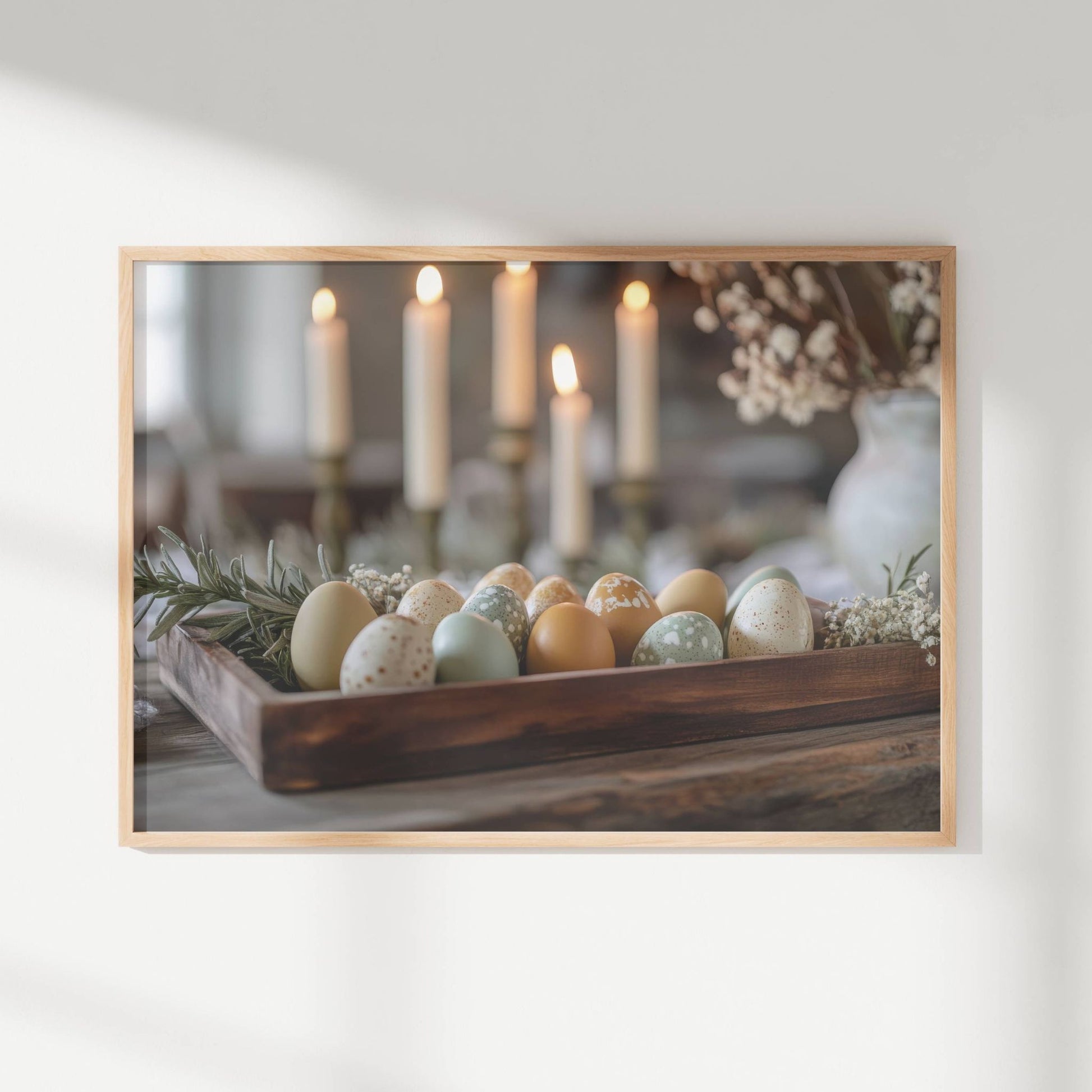 Med delikate pastellfargede egg i en rustikk trekasse, omgitt av grønne kvister og levende lys, formidler dette motivet en tidløs og elegant stemning. Illustrasjon viser motivet som plakat uten hvit kant i ramme.
