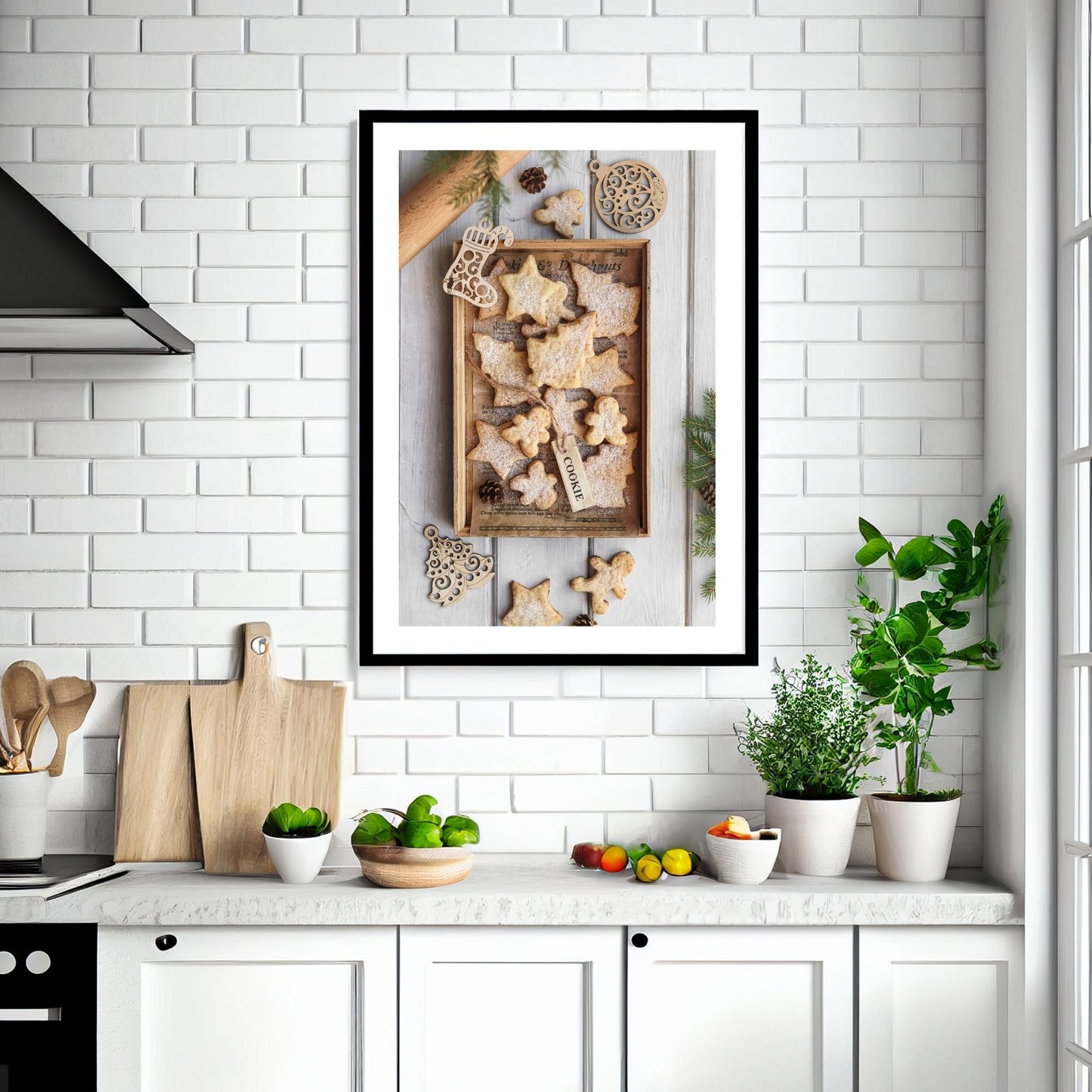 Plakat med dekorativt førjulsmotiv, pepperkaker med melisdryss. Illustrasjonen viser plakaten i sort ramme som henger på en vegg over en kjøkkenbenk.
