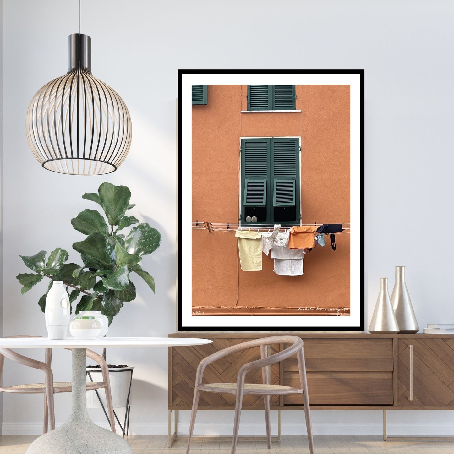 Plakat viser motiv fra Riomaggiore, en av de fem byene i Cinque Terre ved Liguriakysten i Italia. Riomaggiore ligger lengst østover av de 5 byene. Her er det som i alle Italienske byer, klestørk på kryss og tvers på alle husfasader. På plakaten er det en oransje fasadevegg med et vindu med grønne skodder. Under vinduet henger dagens klesvask til tørk.  Plakaten som har en hvir kant rundt, er innrammet i sort ramme.