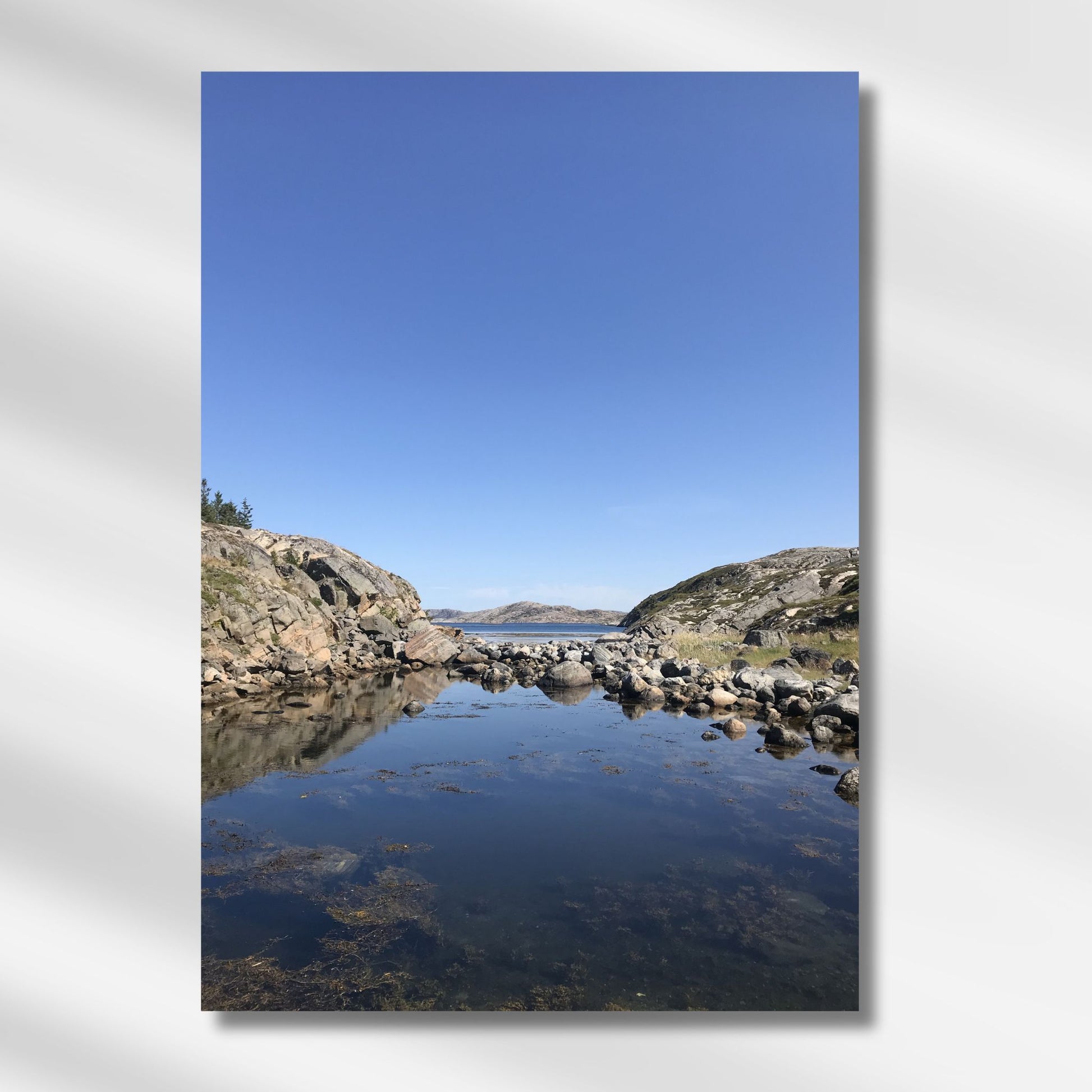 Mellom to klippeformasjoner åpner landskapet seg mot hav og øyer. Dette er et motiv for deg som søker ro, klarhet og den stille storheten som bare norsk kystnatur kan gi. Illustrasjon viser motivet på lerret.