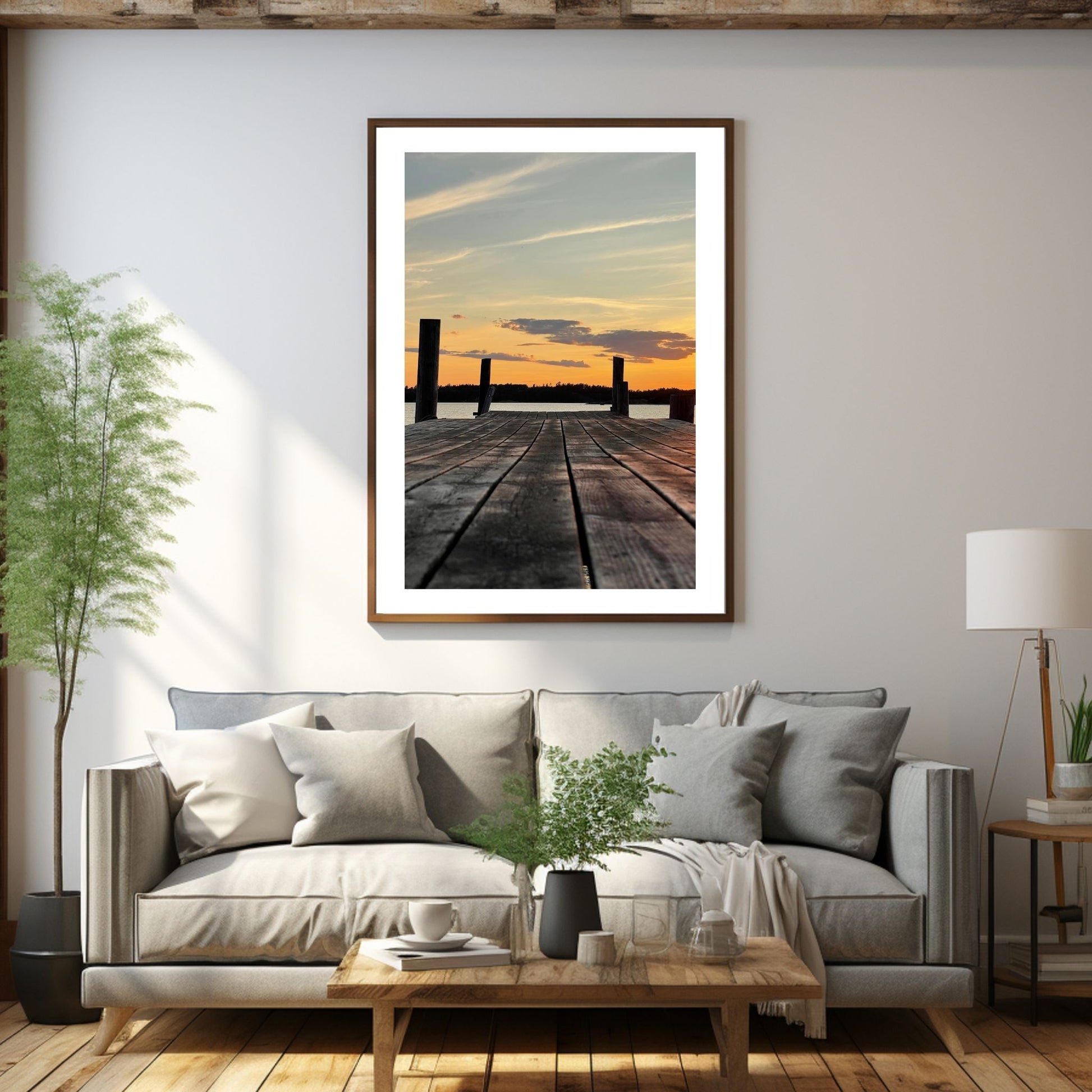 Nydelig solnedgang ved Krokstadfjorden ved Saltnes. Motiv av en brygge som går ute i sjøen, og en sol som er i ferd med å gå ned på en oransje himmel. Fås både som plakat og på lerret. Miljøbildet viser plakaten i en eikeramme som henger på en vegg over en sofa.