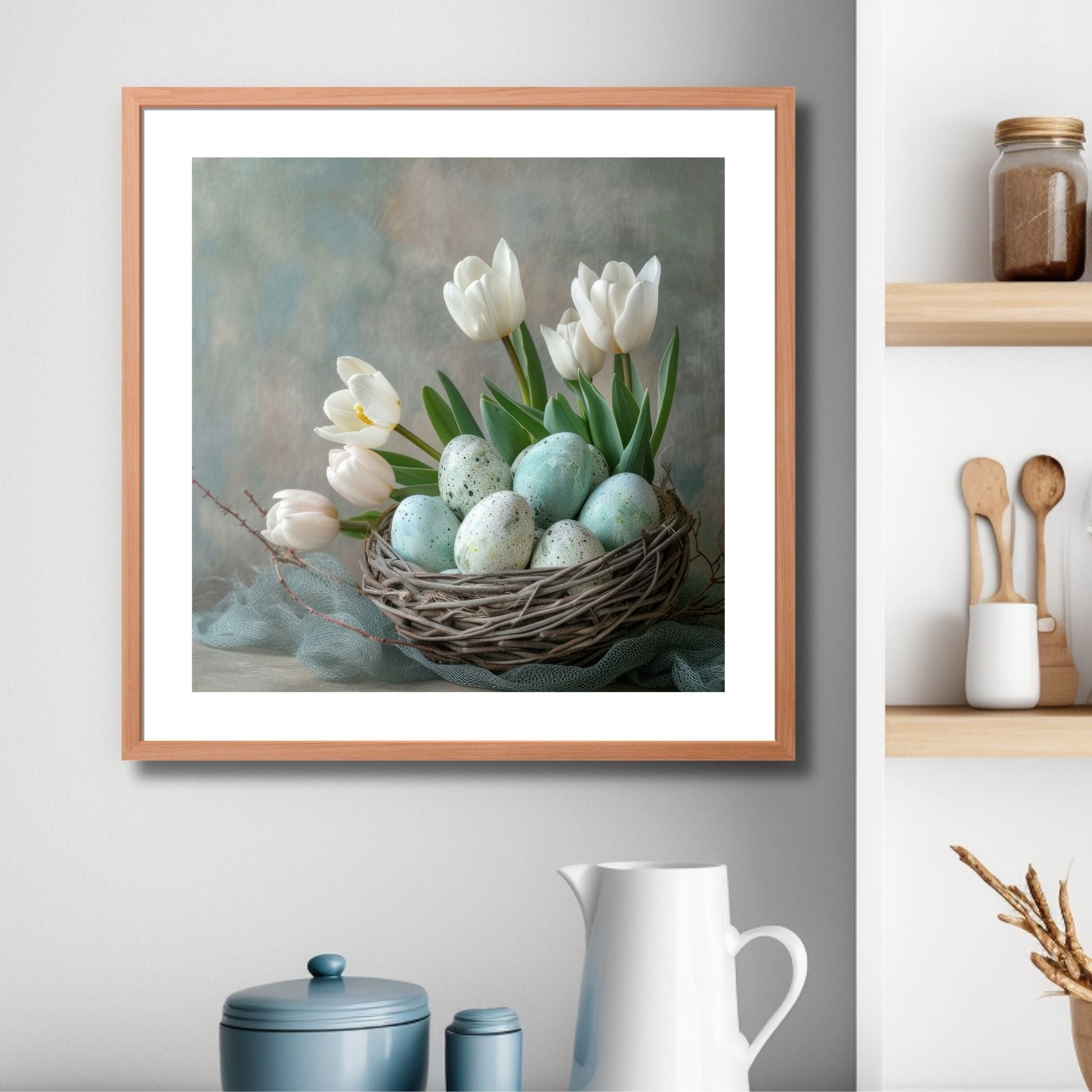 Grafisk illustrasjon som viser hvite tulipaner og lyseblå og hvite påskeegg som ligger vakkert plassert i et rede av kvister. Illustrasjonsfoto viser plakaten i kvadratisk format i en ramme over en kjøkkenbenk.