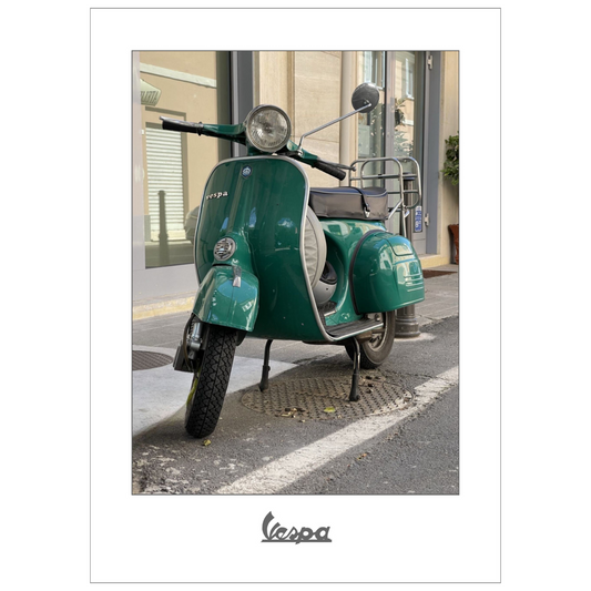 Fotografi av en grønn Vespa parkert foran en bygning i en gate i Italia. Plakaten har en hvit kant.