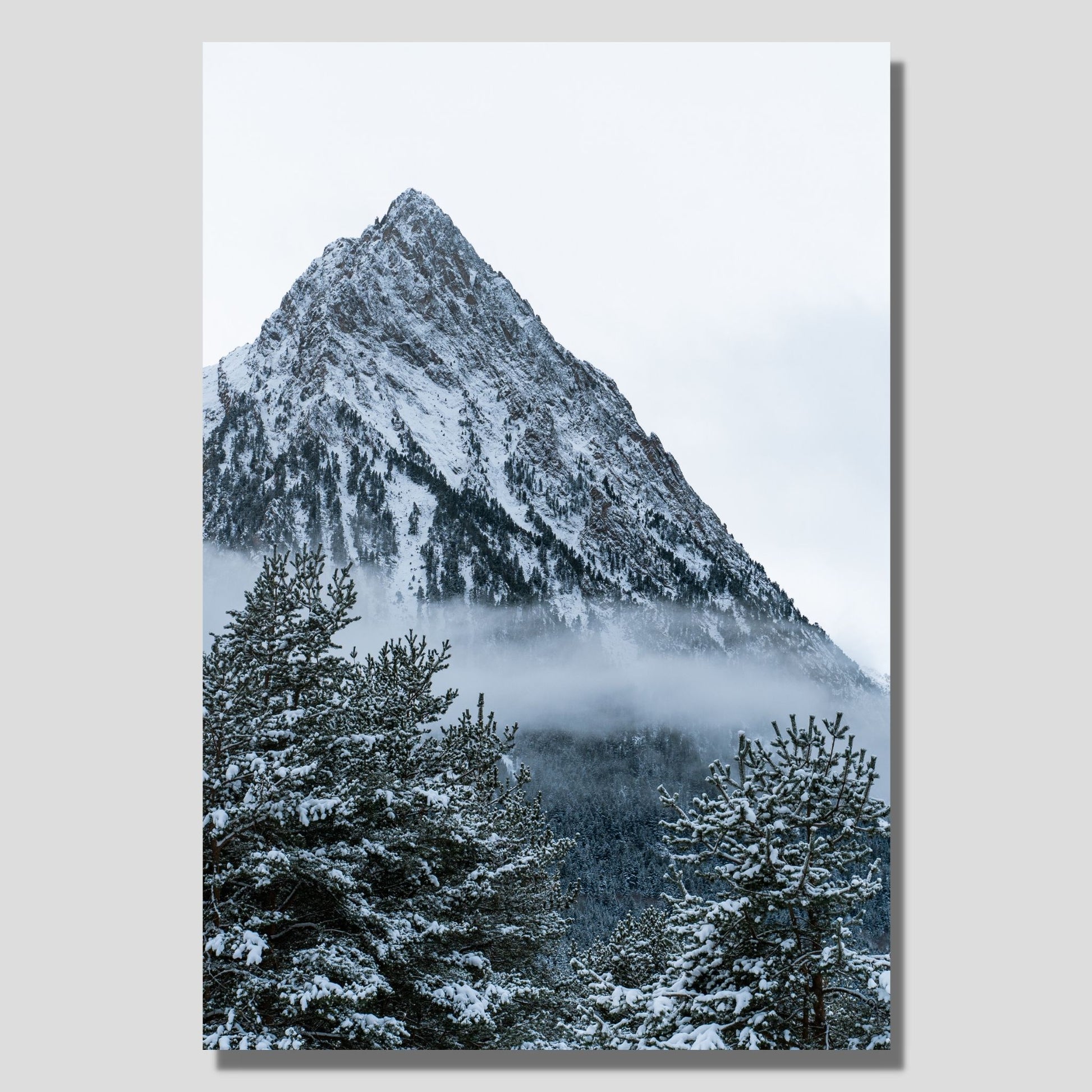 Snøkledd granskog  og ruvende fjelltopp. Fotografi  som plakat eller lerret. Plakat har en hvit kant rundt som gir dybde og fremhever motivet. Illustrasjonen viser fotografiet som lerretsmotiv hengende på en vegg.