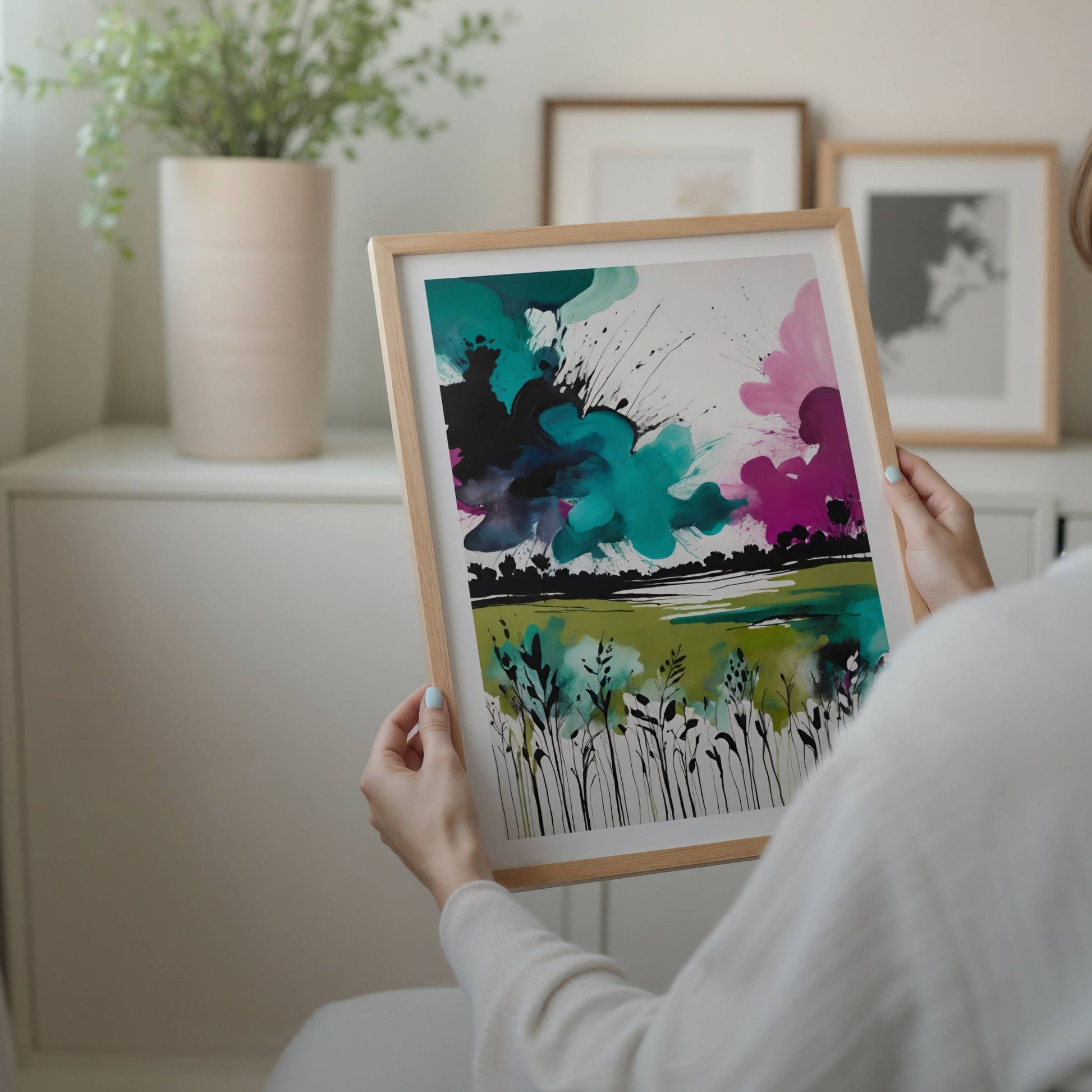 Wild Horizon – abstrakt naturplakat forener det ville og det vakre i ett levende kunstverk. Med kraftfulle blekk-lignende strøk og fargeeksplosjoner i turkis, grønt og rosa. Illustrasjon viser plakat med hvit kant i eik ramme.