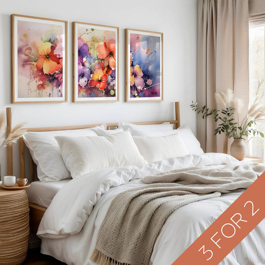 Color Splash Bloom Collection med tre fargerike blomsterplakater i akvarellstil vist over seng i lyst nordisk soverom