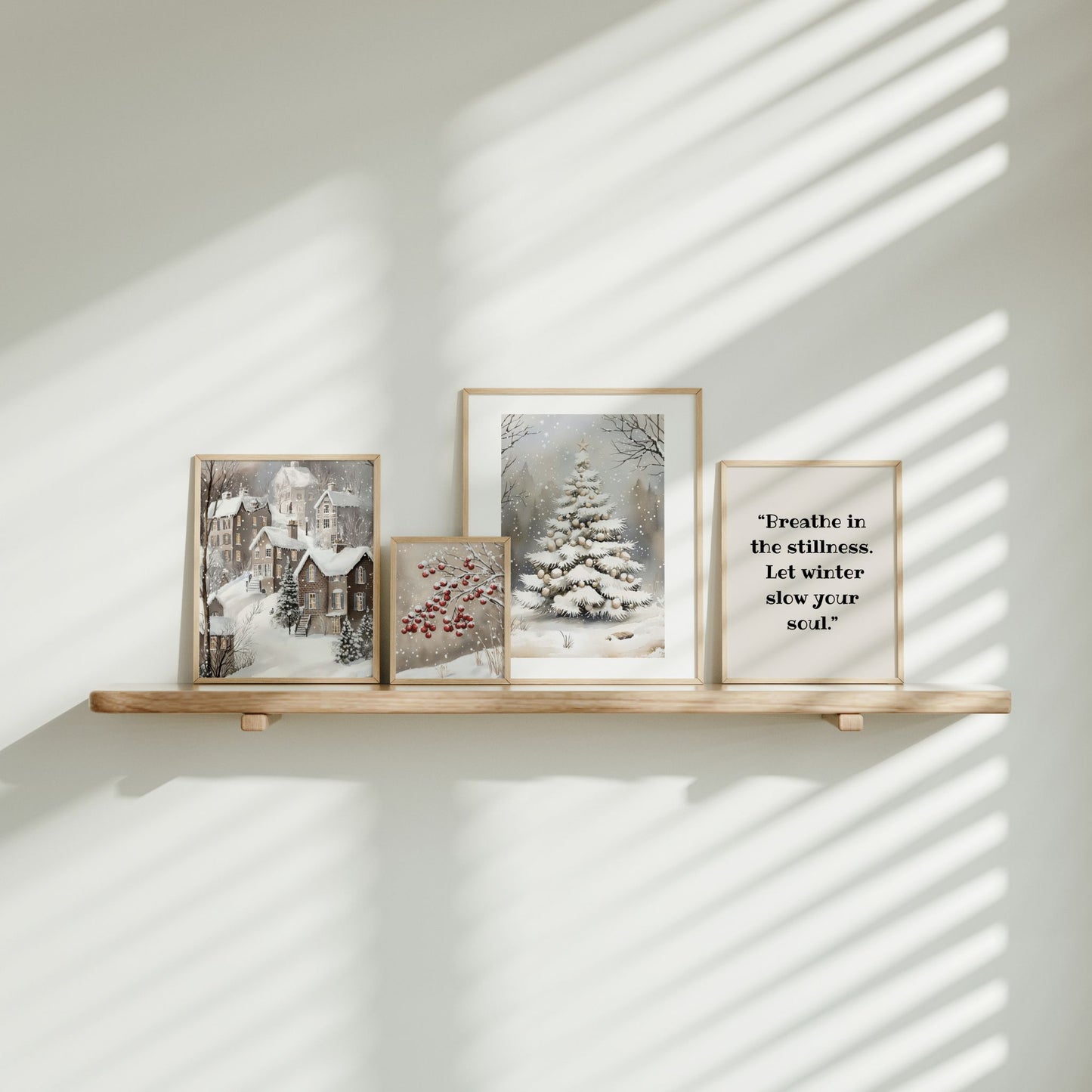 Tekstplakaten “Breathe in the stillness. Let winter slow your soul.” plassert på hylle sammen med vintermotiver i varme beige toner.