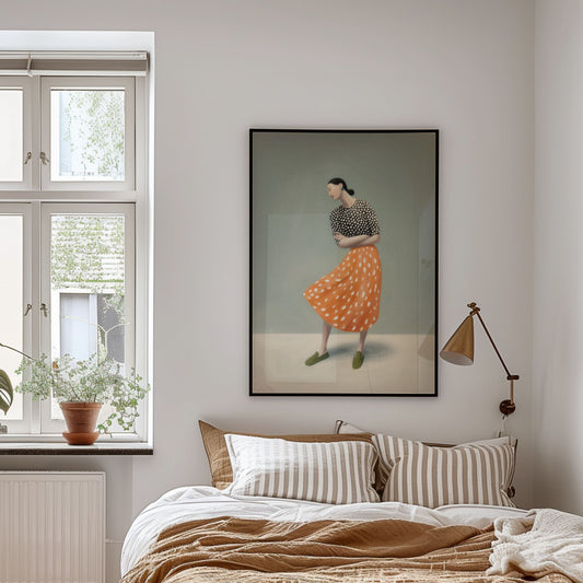 Moderne plakat med kvinne i oransje skjørt i rolig bevegelse, plassert over seng i lyst soverom
