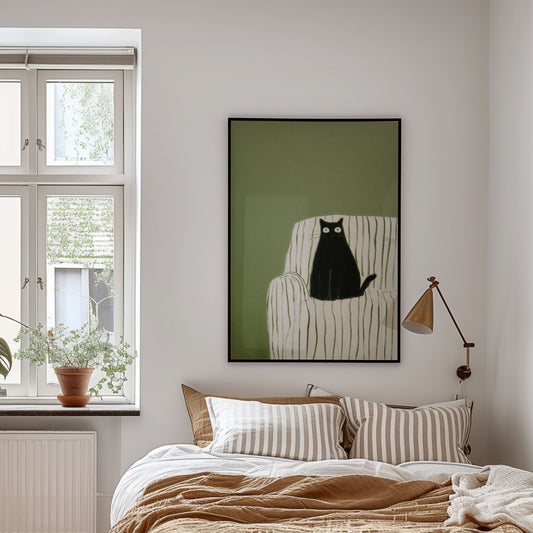 Plakat med sort katt på stripet stol i grønne toner, vist over seng i lyst soverom