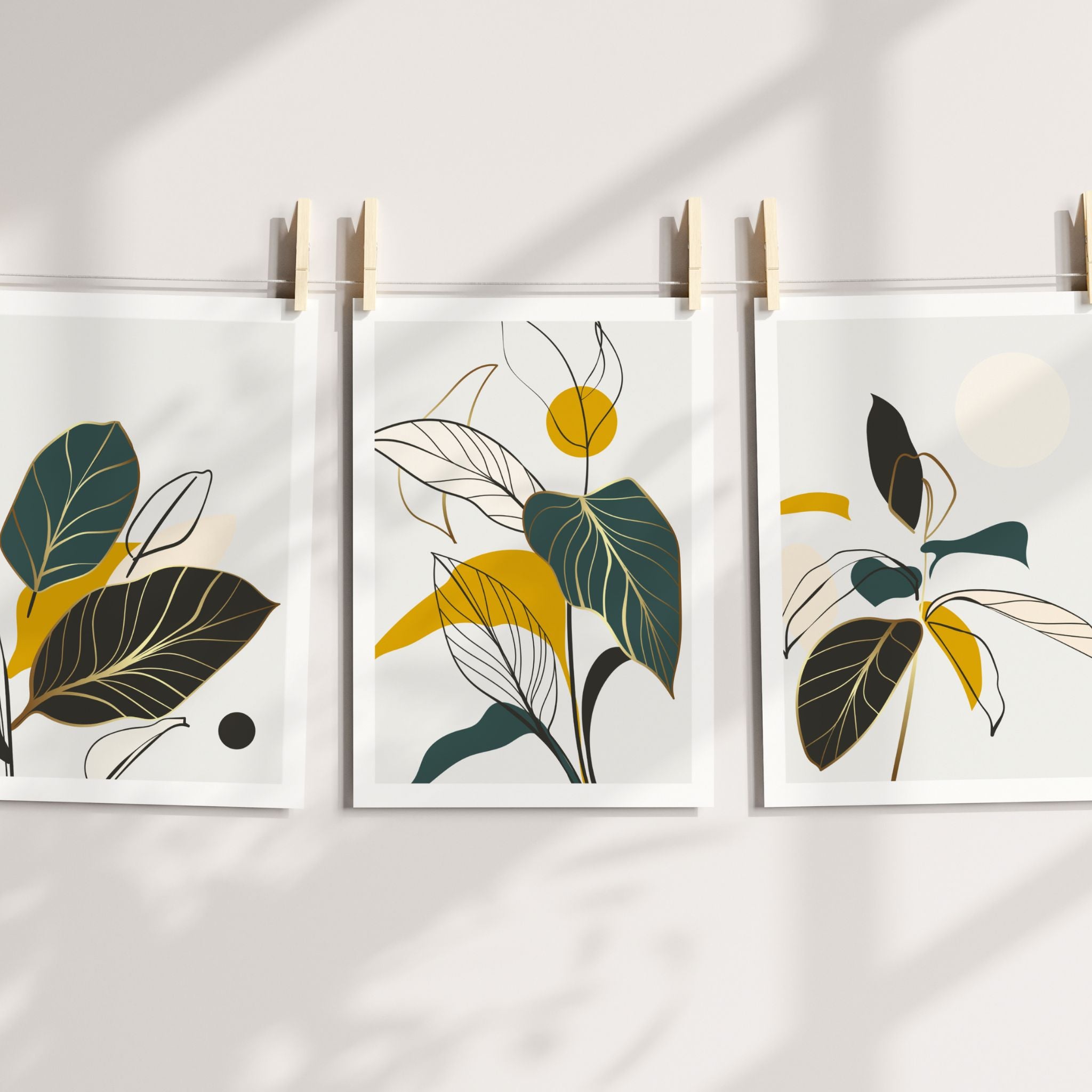 Golden Botanica Trio med tre botaniske plakater i grønne, gylne og sorte toner hengt med treklyper