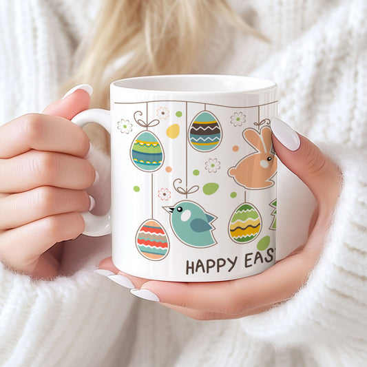 Keramikkrus med illustrasjon av hengende påskeegg, små fugler og kaniner samt teksten Happy Easter, holdt i hendene foran lys bakgrunn.