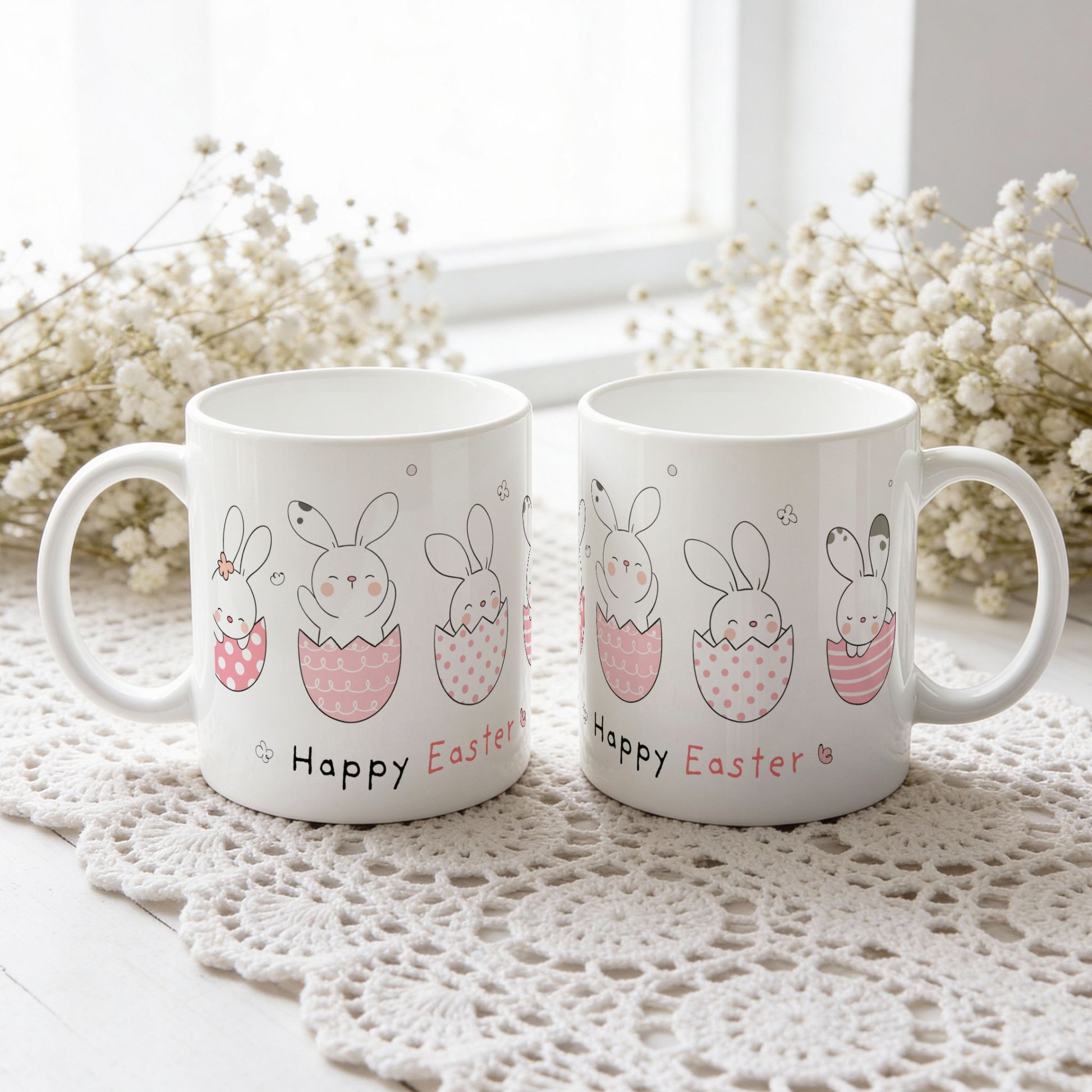 Påskekrus med kaniner i rosa mønstrede egg og teksten Happy Easter, vist fra begge sider på hvit blondeduk.