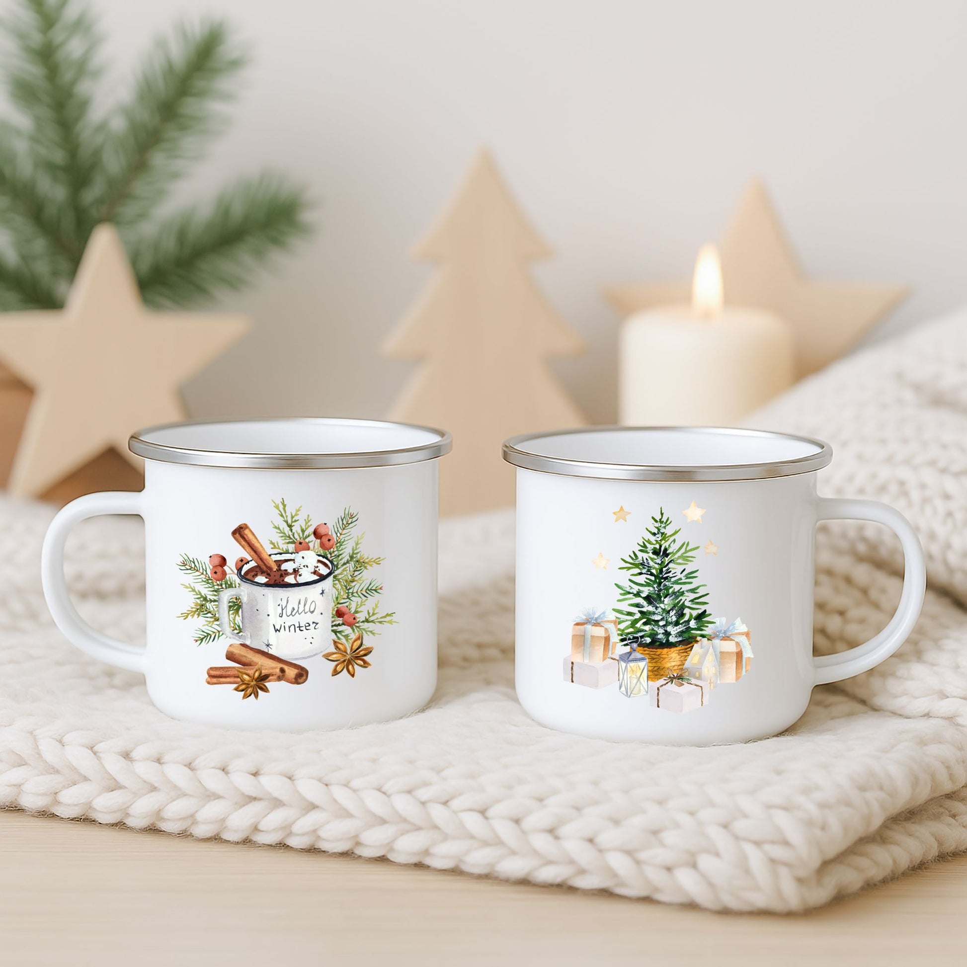 Julekrus i hvit emalje med motiv av vinterkakao med kanel og lite juletre med gaver, fotografert på lys strikket duk med dempet juledekor i bakgrunnen.