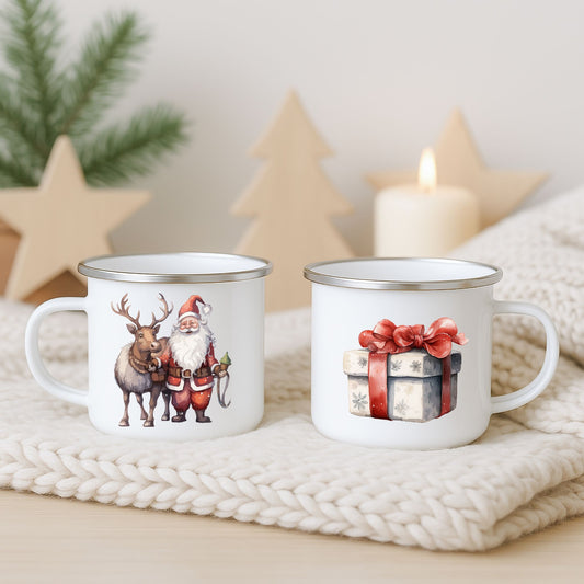 Hvitt emaljekrus med to julemotiver: nisse og reinsdyr på én side og gavepakke med rød sløyfe på den andre, fotografert på lys strikket duk med dempet juledekor i bakgrunnen.