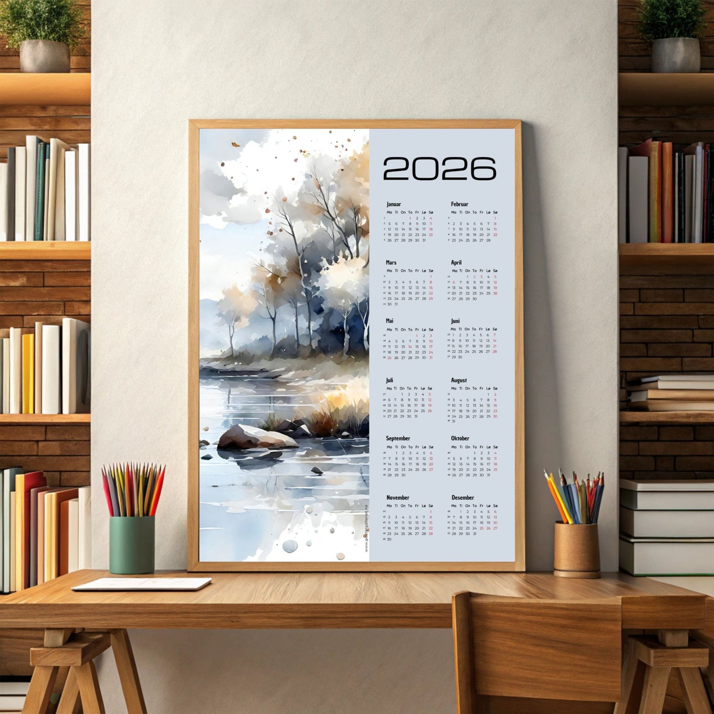 Kalender 2026 med akvarellmotiv av høstlig landskap ved vann, i lyse og varme toner. Illustrasjon viser kalender i eik ramme.