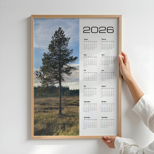 Kalender 2026 med foto av en stor furu i kveldslys. Illustrasjon viser kalender i eik ramme.