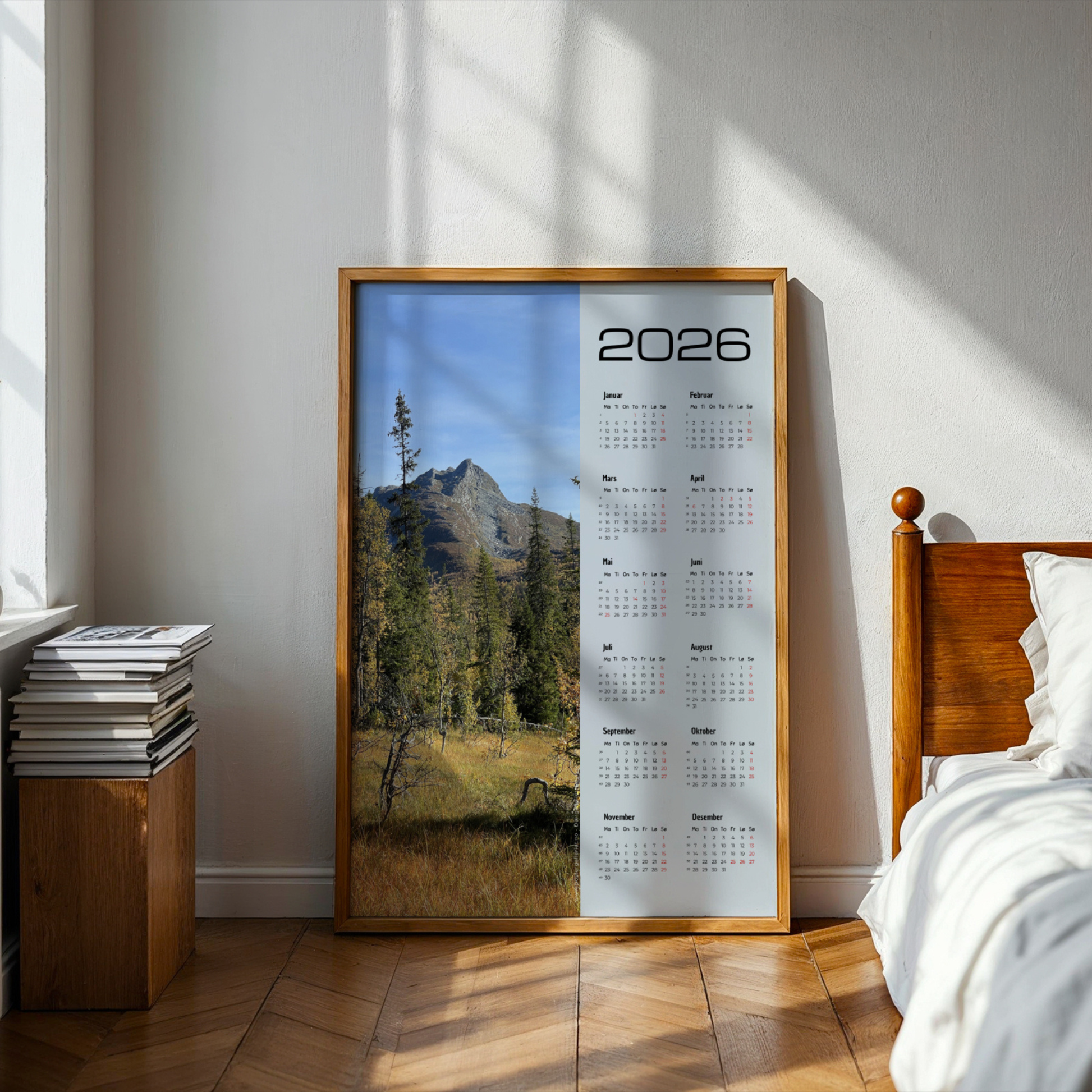 Kalender 2026 med foto av høstskog og fjell ved Dærgafjellet i Røyrvik. Illustrasjon viser kalender i eik ramme på et soverom.
