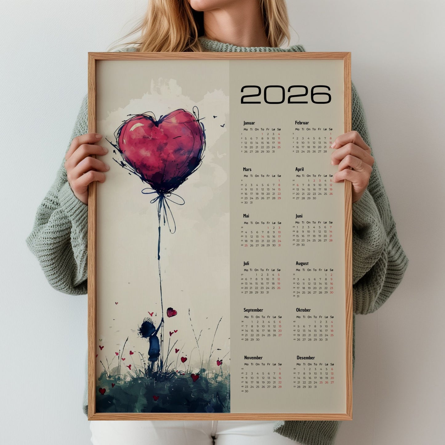 Kalender 2026 med illustrert motiv av jente og stor rød hjerteballong, med tydelig kalenderdel til høyre. Illustrasjon iser kalender i eik ramme.